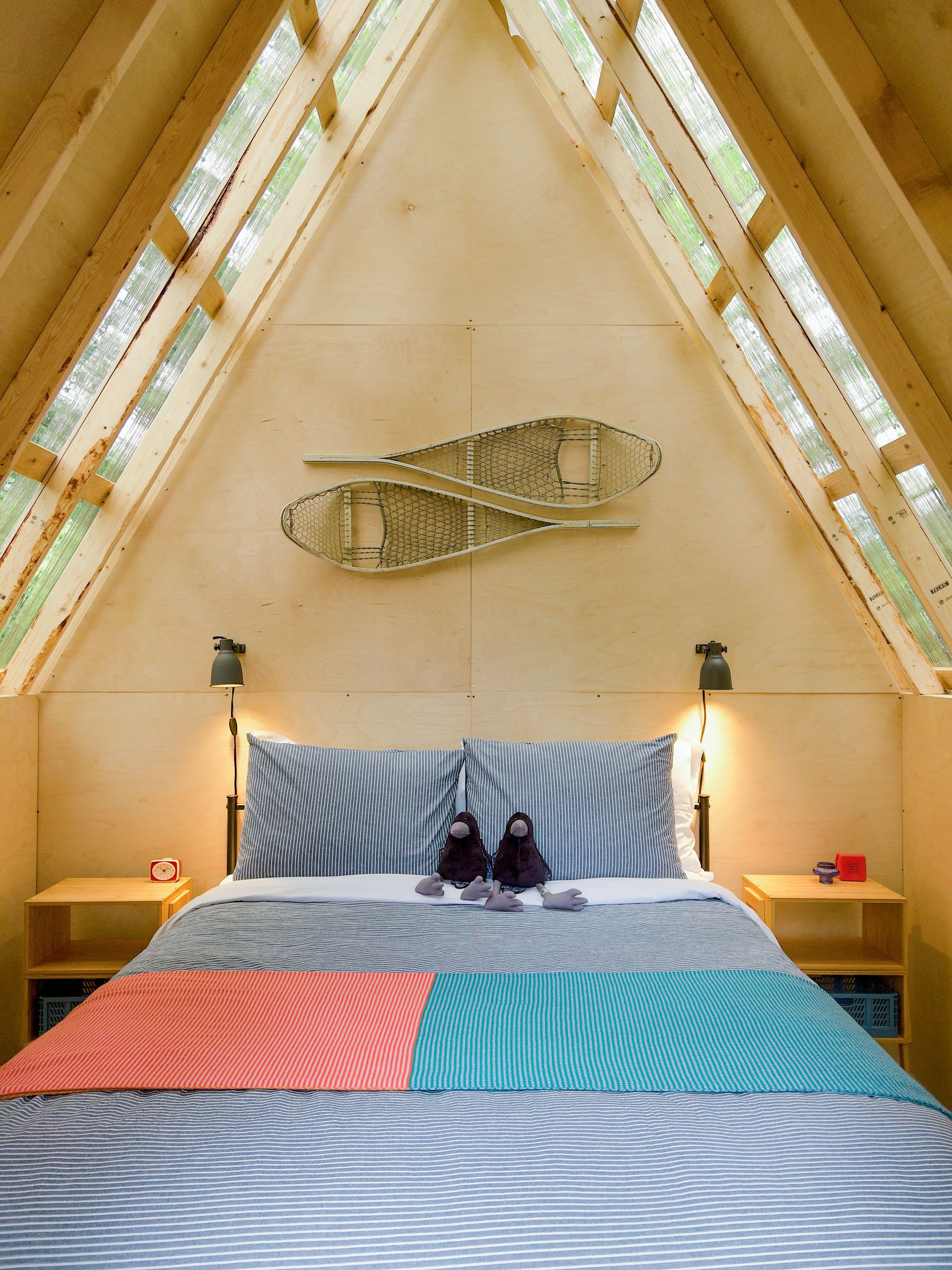 a bedroom with a bed , two lamps and a painting on the wall .