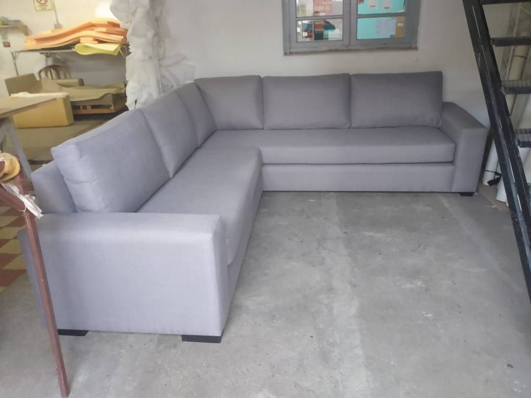 Sofá modular gris en una zona de almacenamiento con estantes y suelo enmoquetado.