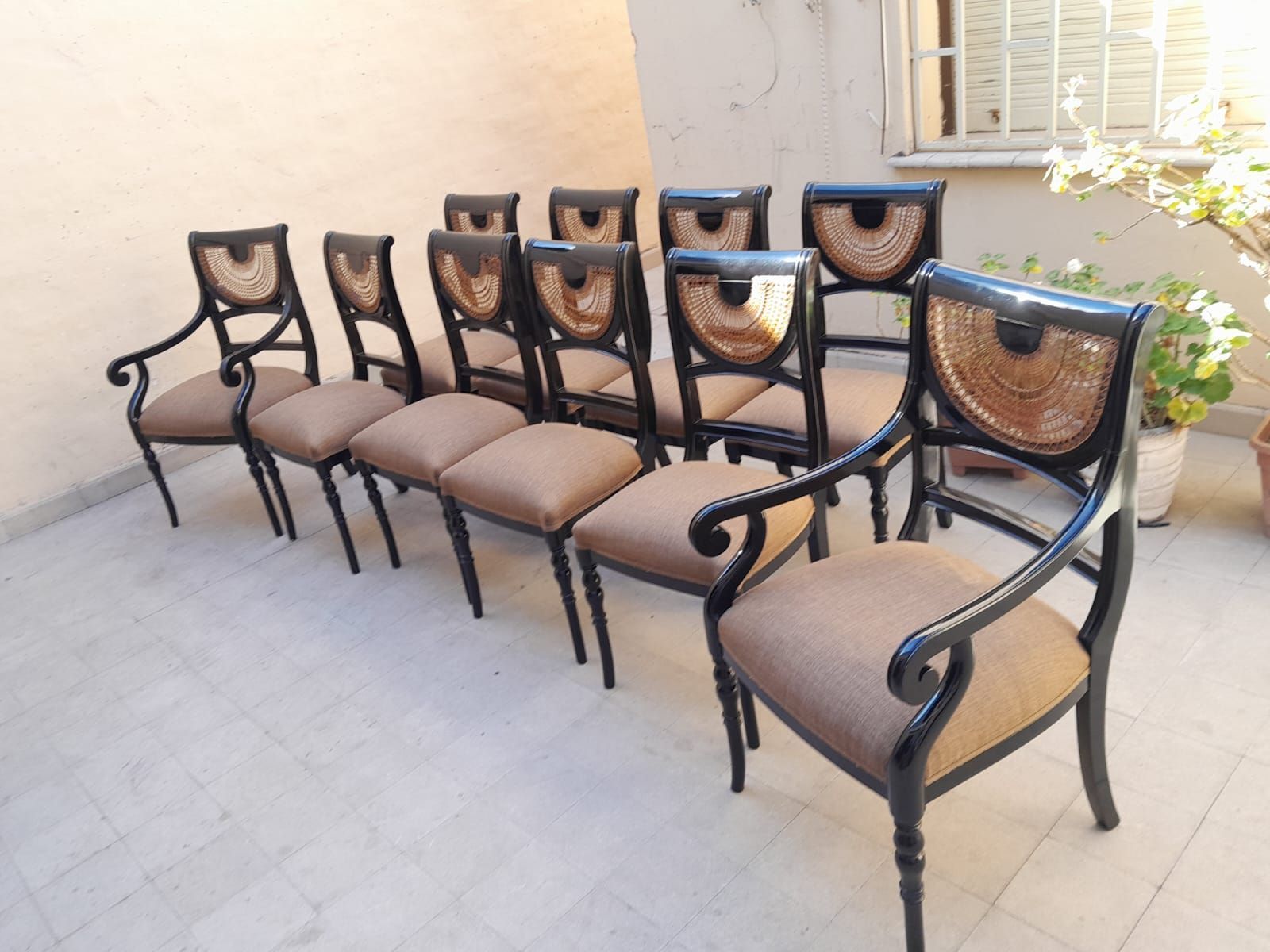Hilera de sillas marrones acolchadas con armazón negro dispuestas al aire libre en un patio.