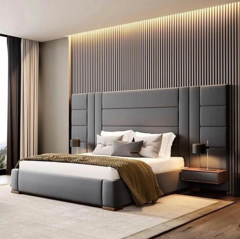 Dormitorio moderno en tonos grises con cama tapizada, pared decorativa a rayas, iluminación cálida y decoración neutra.