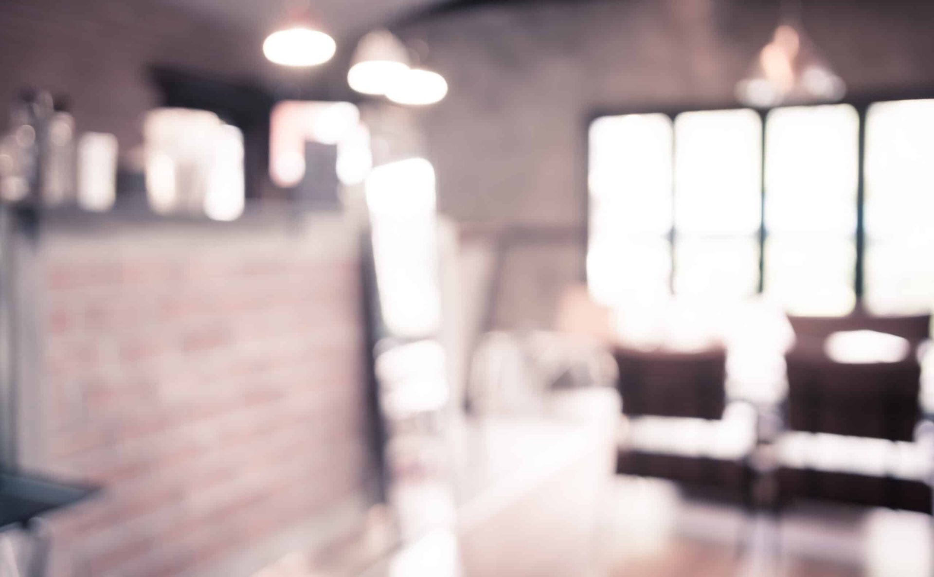 Blurred café interior with bright windows, brick counter, and seating in soft light