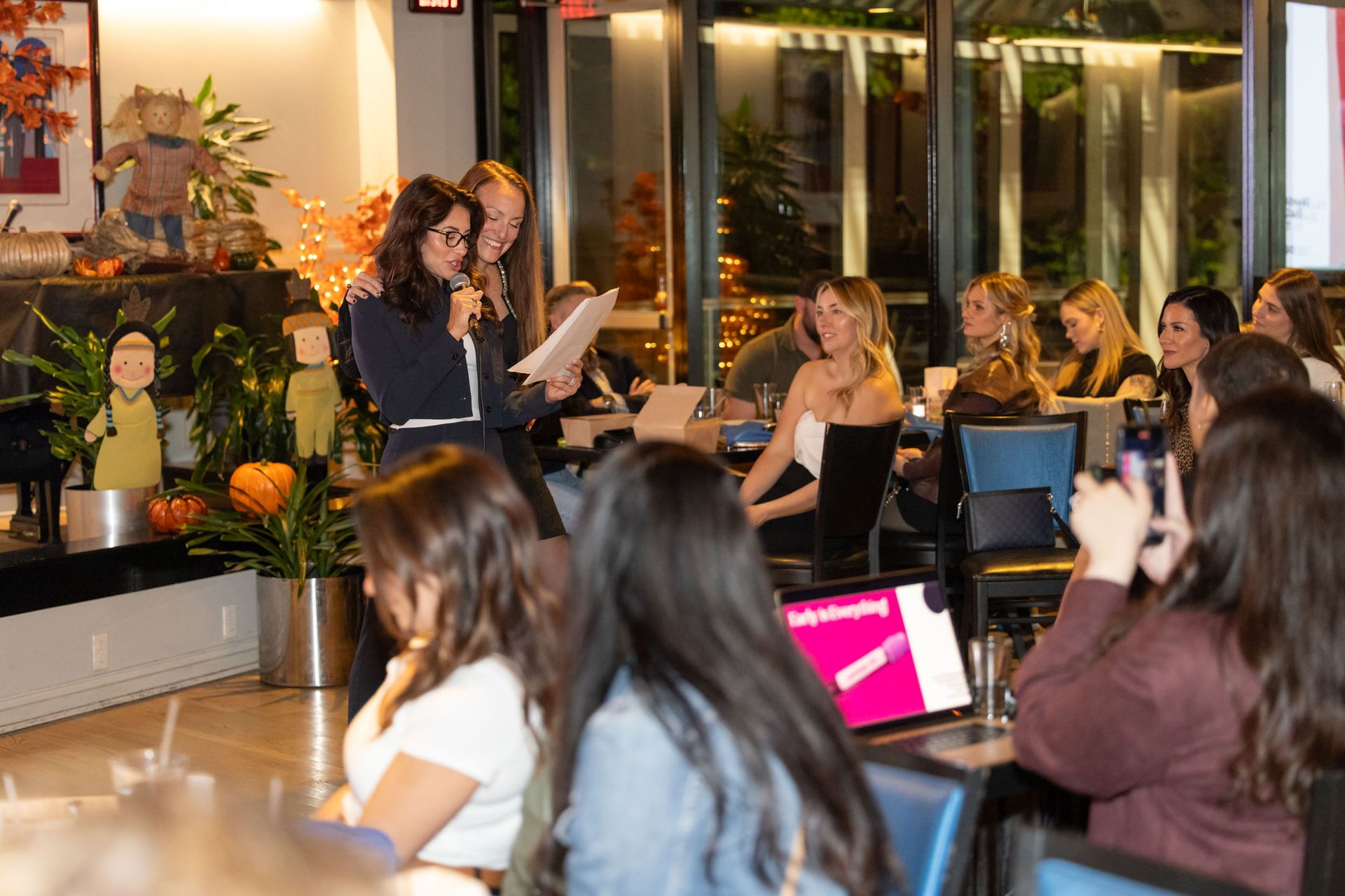 A woman is giving a presentation to a group of people in a restaurant.