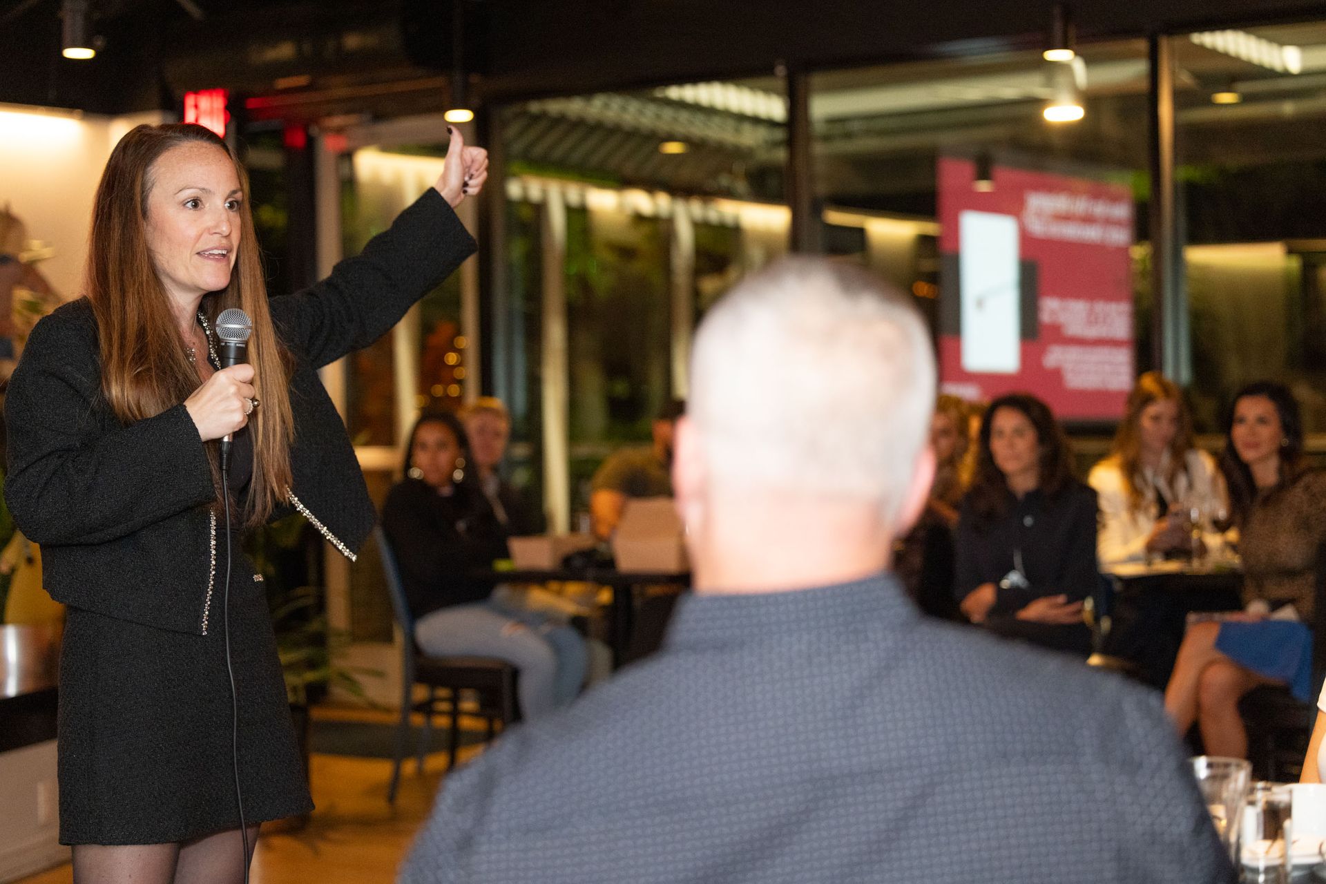 A woman is holding a microphone in front of a group of people.