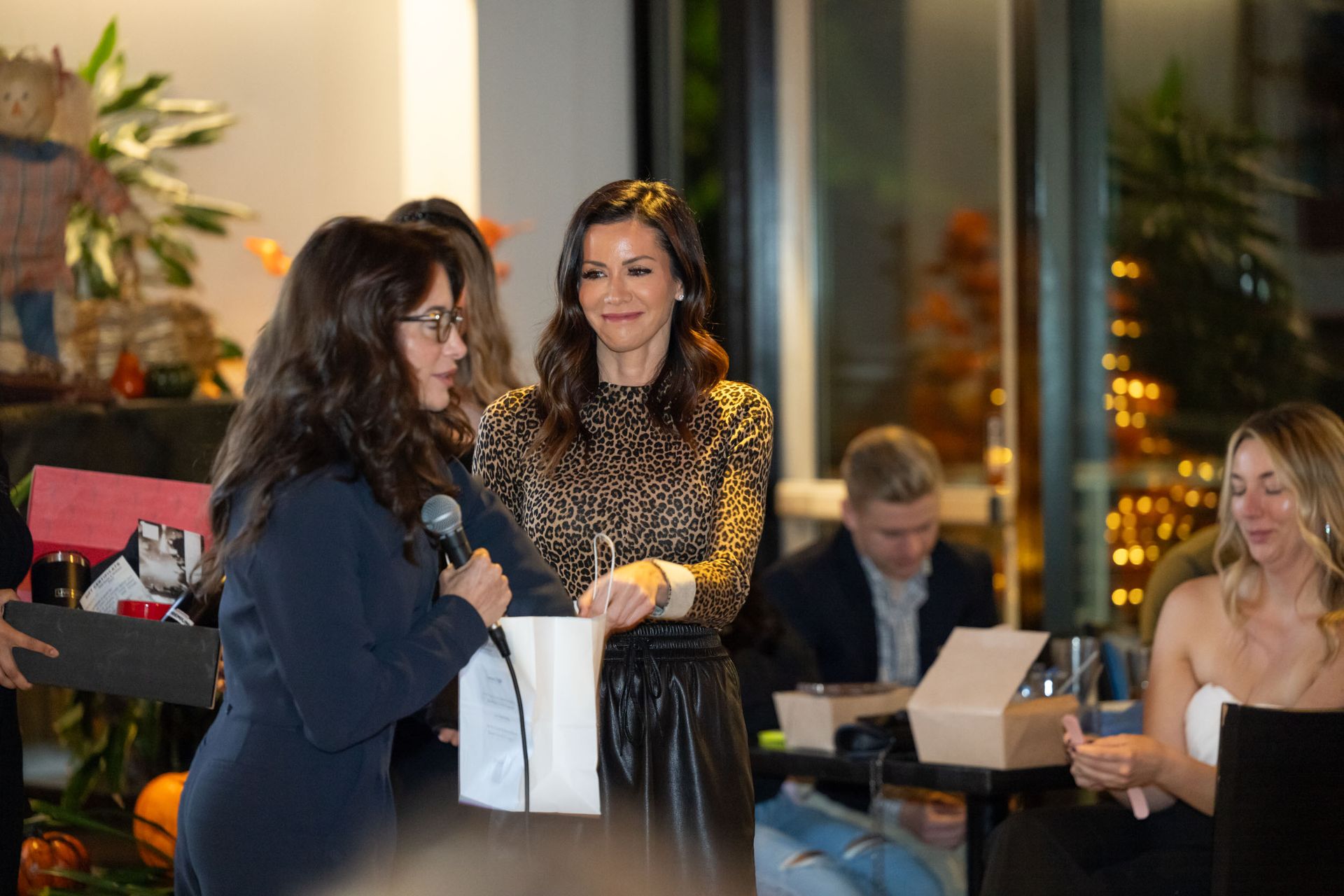 A woman is holding a microphone while standing next to another woman.