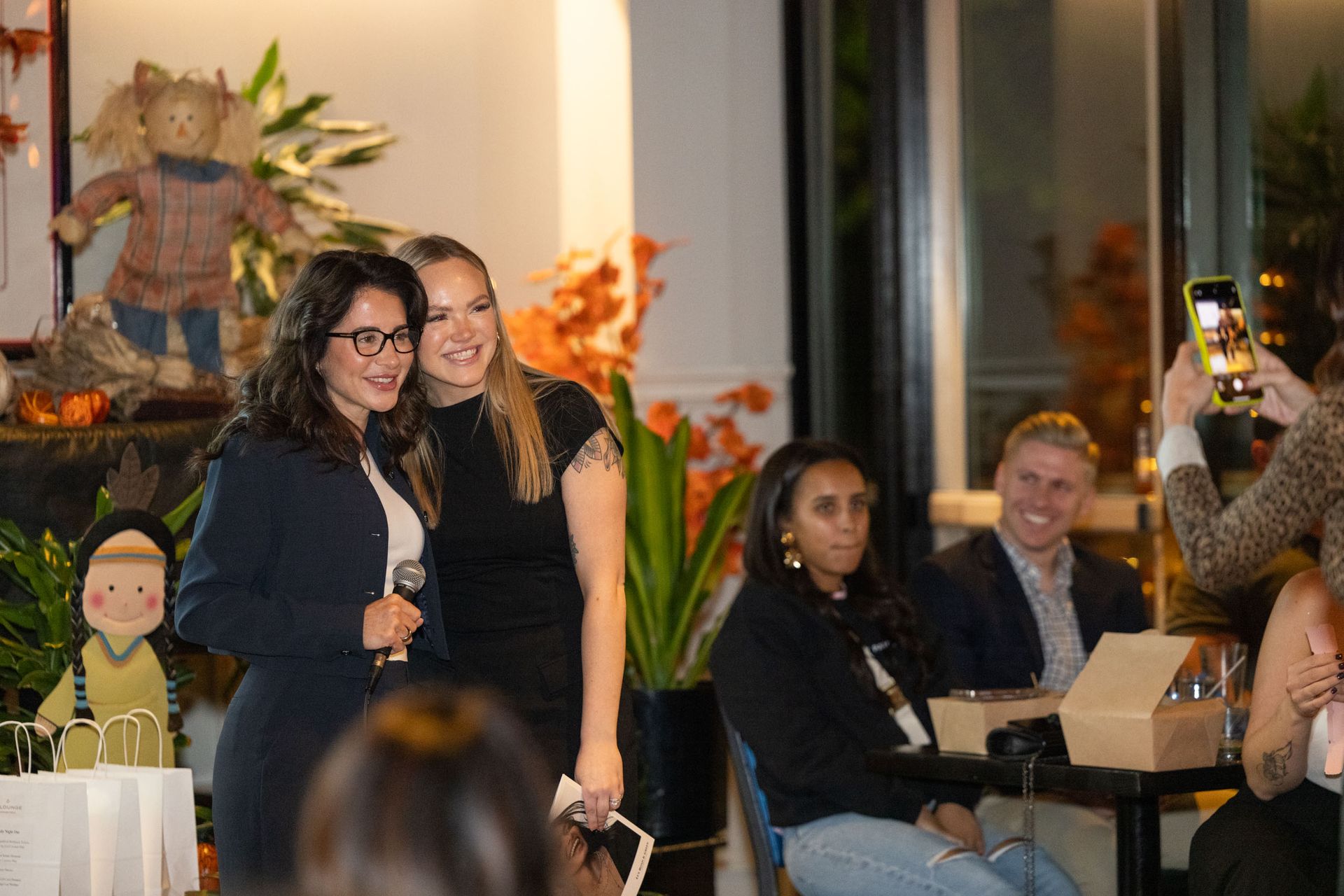 Two women are standing next to each other in front of a microphone.