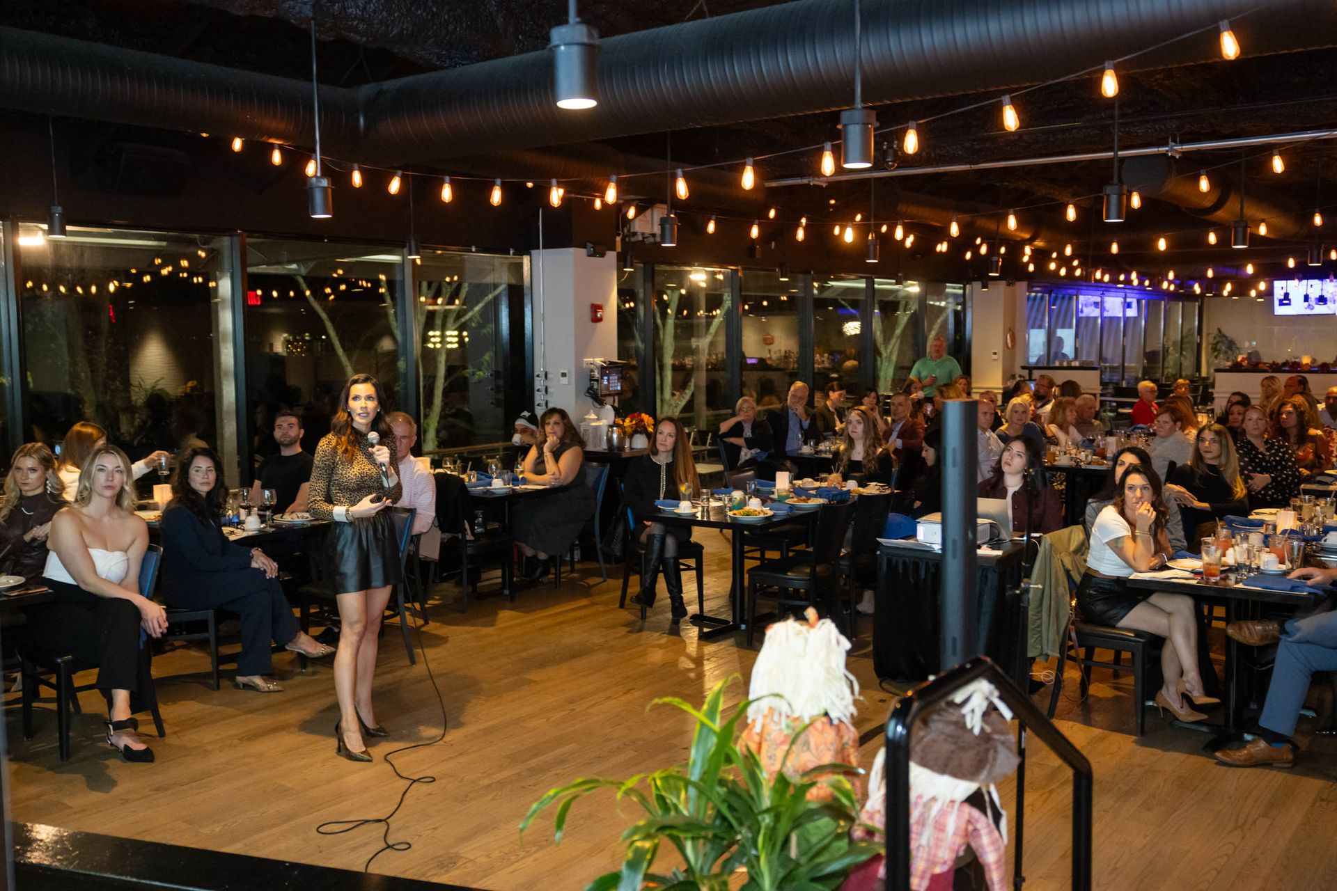 A woman is standing in front of a crowd of people in a restaurant.