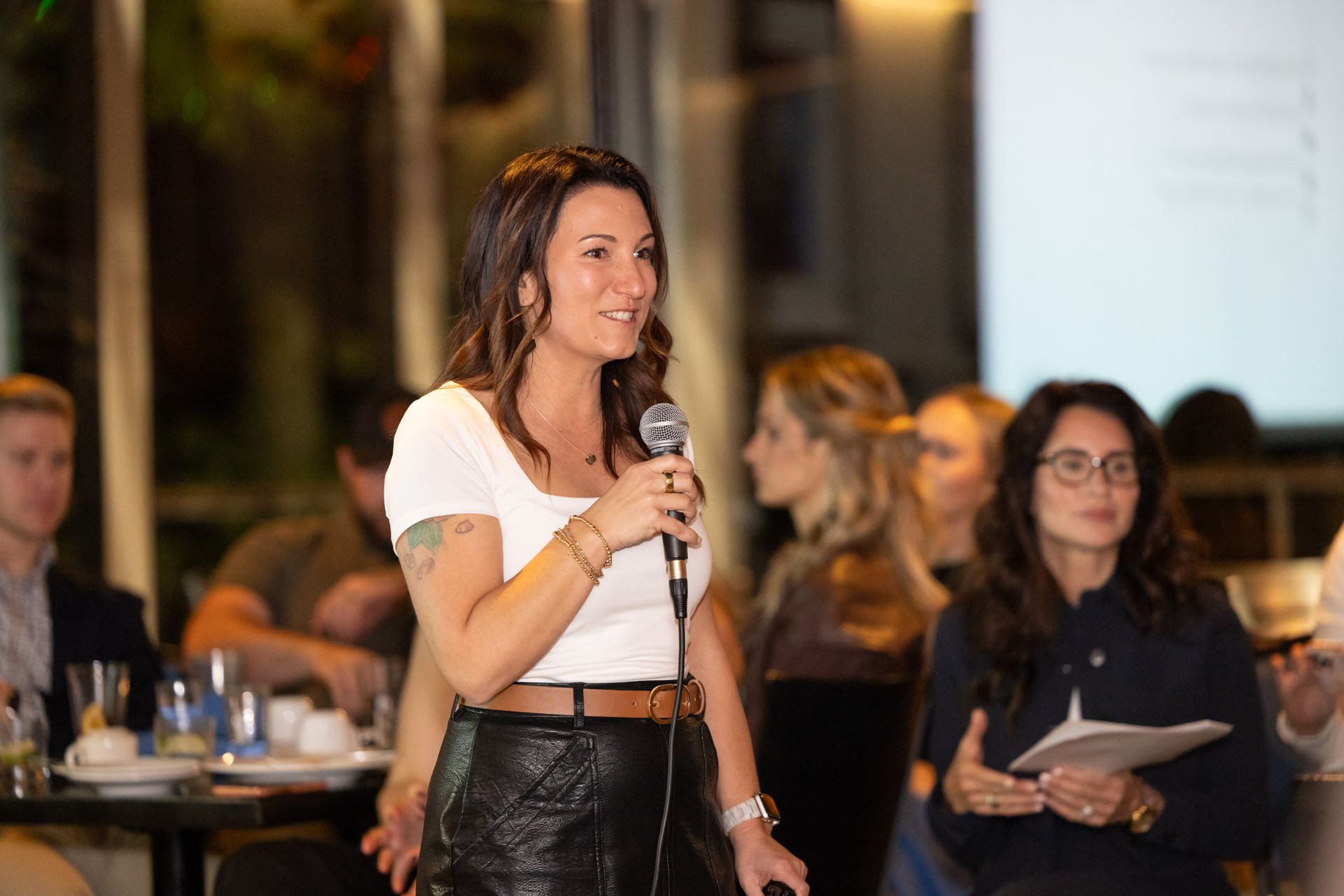 A woman is holding a microphone in front of a group of people.