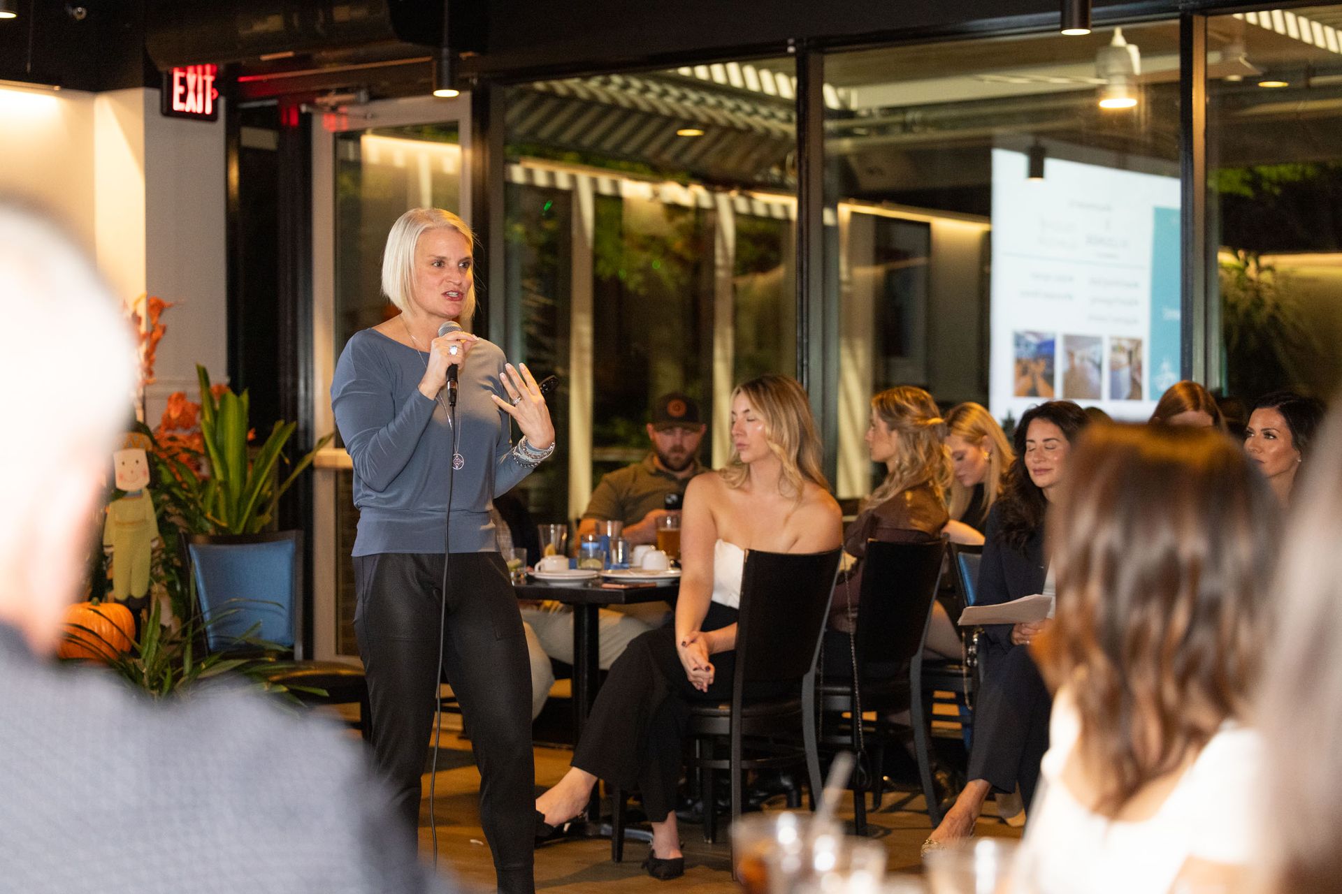 A woman is standing in front of a microphone talking to a group of people.