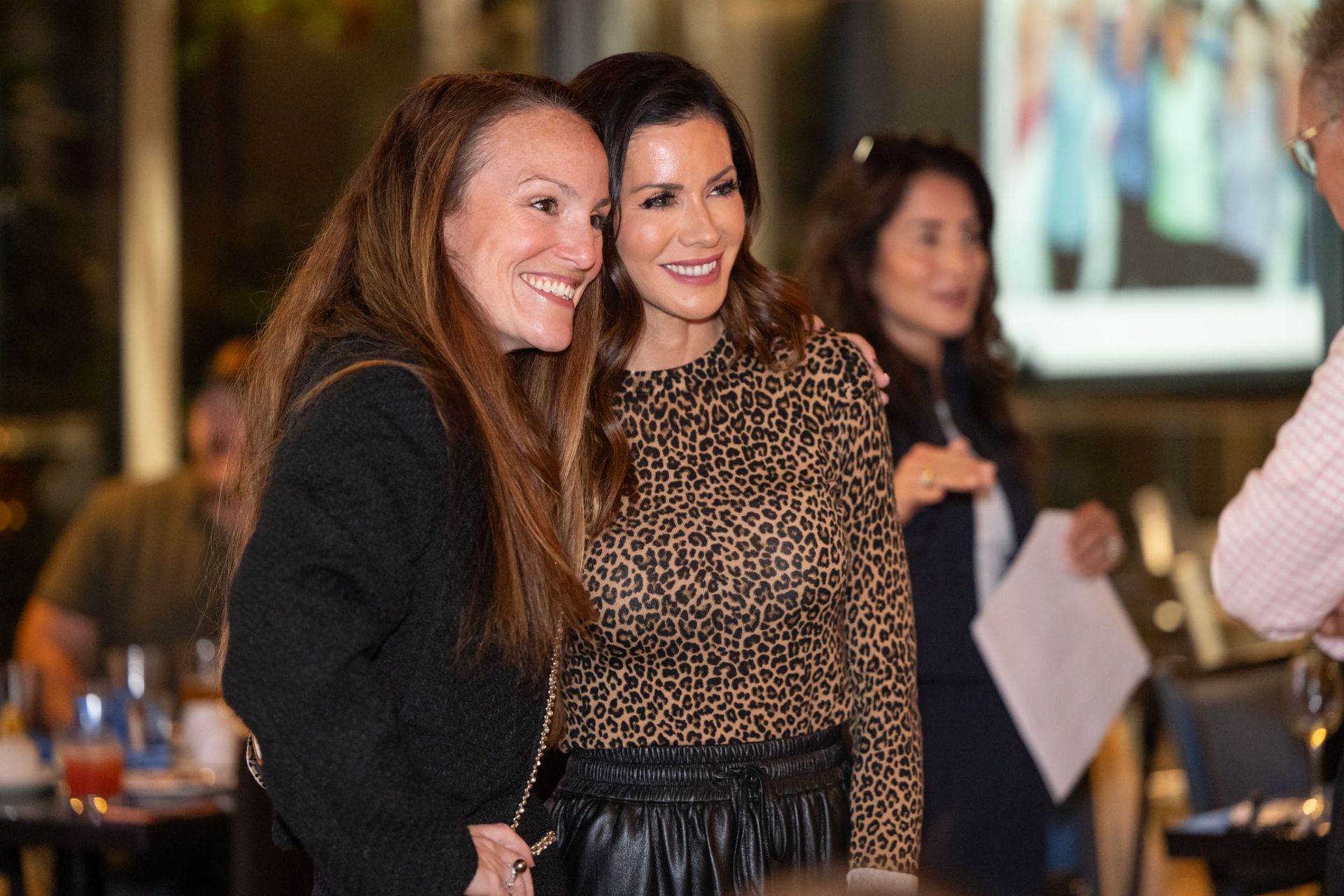 Two women are posing for a picture together in a restaurant.