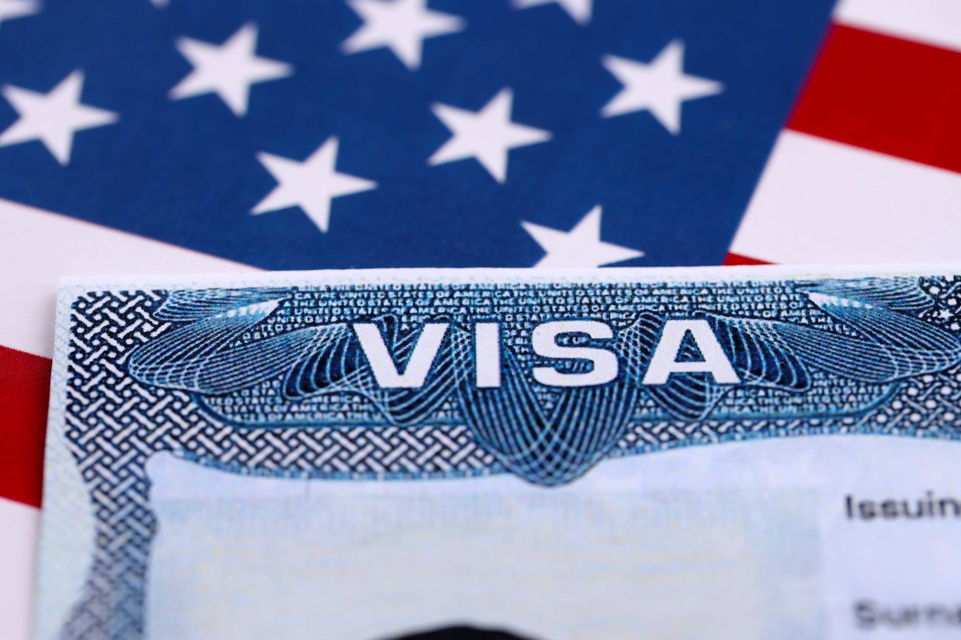 A close-up of a U.S. visa document resting on top of an American flag.