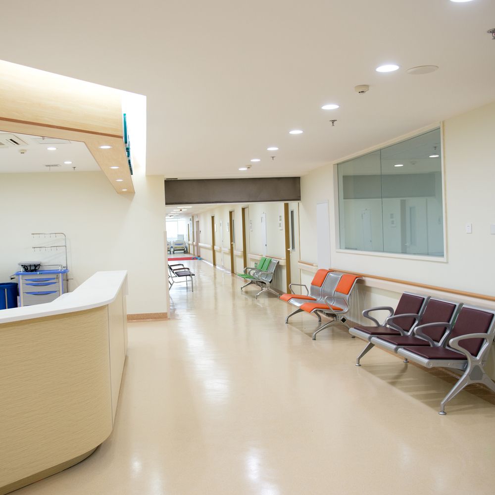 A Long Hallway in a Hospital With Chairs and a Counter — Charmhaven Carpets In Charmhaven, NSW