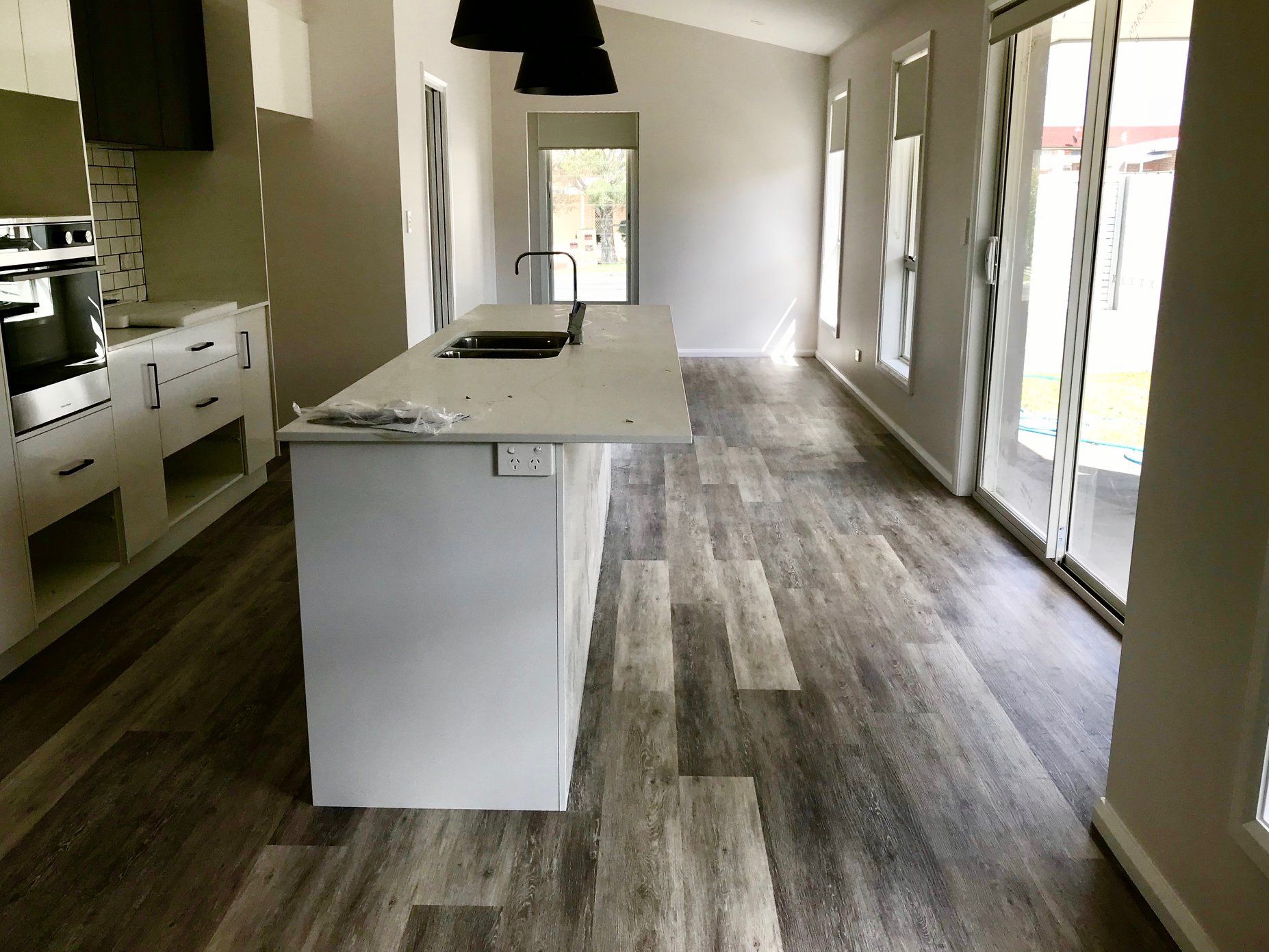 A kitchen with a large island and sliding glass doors — Charmhaven Carpets in Central Coast, NSW