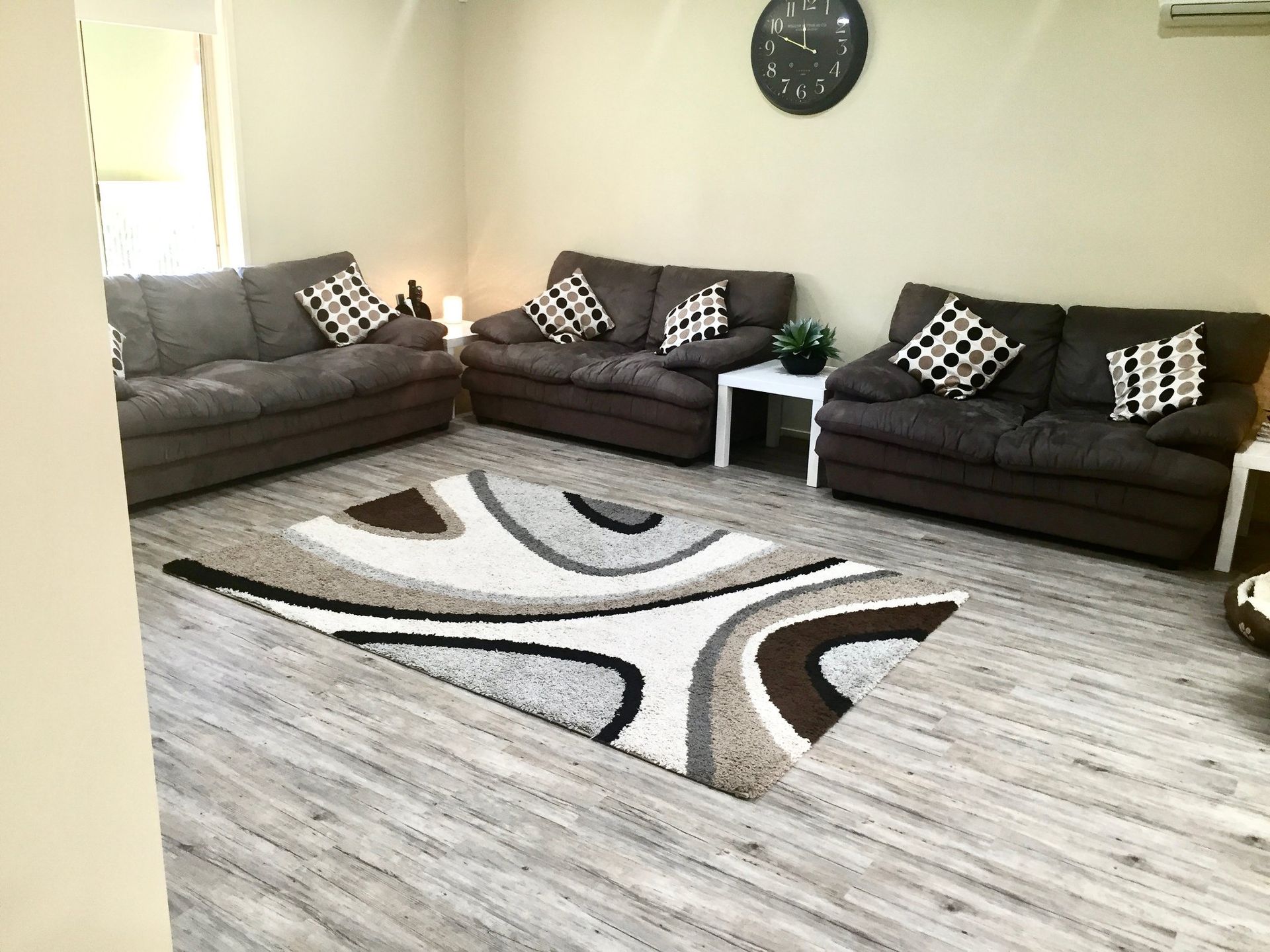 Living Room with Dark Sofas, Patterned Pillows — Charmhaven Carpets In Charmhaven, NSW