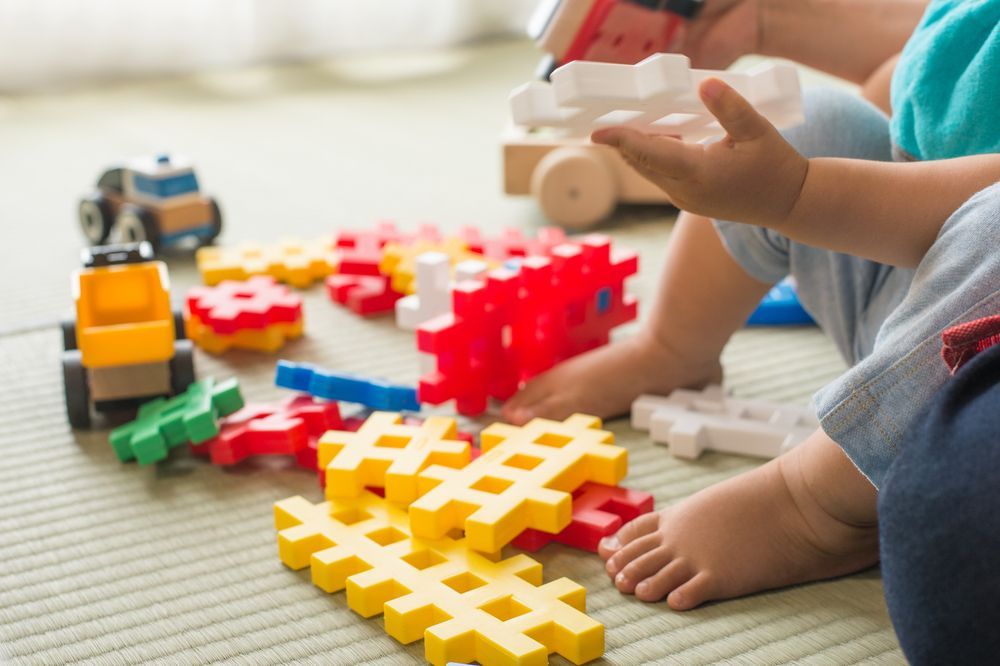A Baby is Playing With Toys on the Floor — Charmhaven Carpets In Charmhaven, NSW