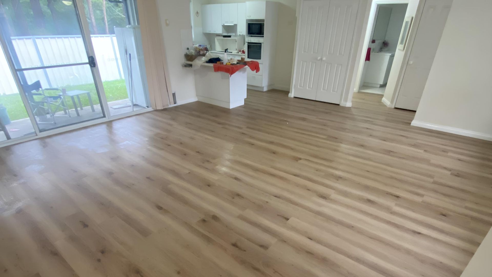 A Living Room With a Wooden Floor and a Kitchen in the Background — Charmhaven Carpets in Central Coast, NSW