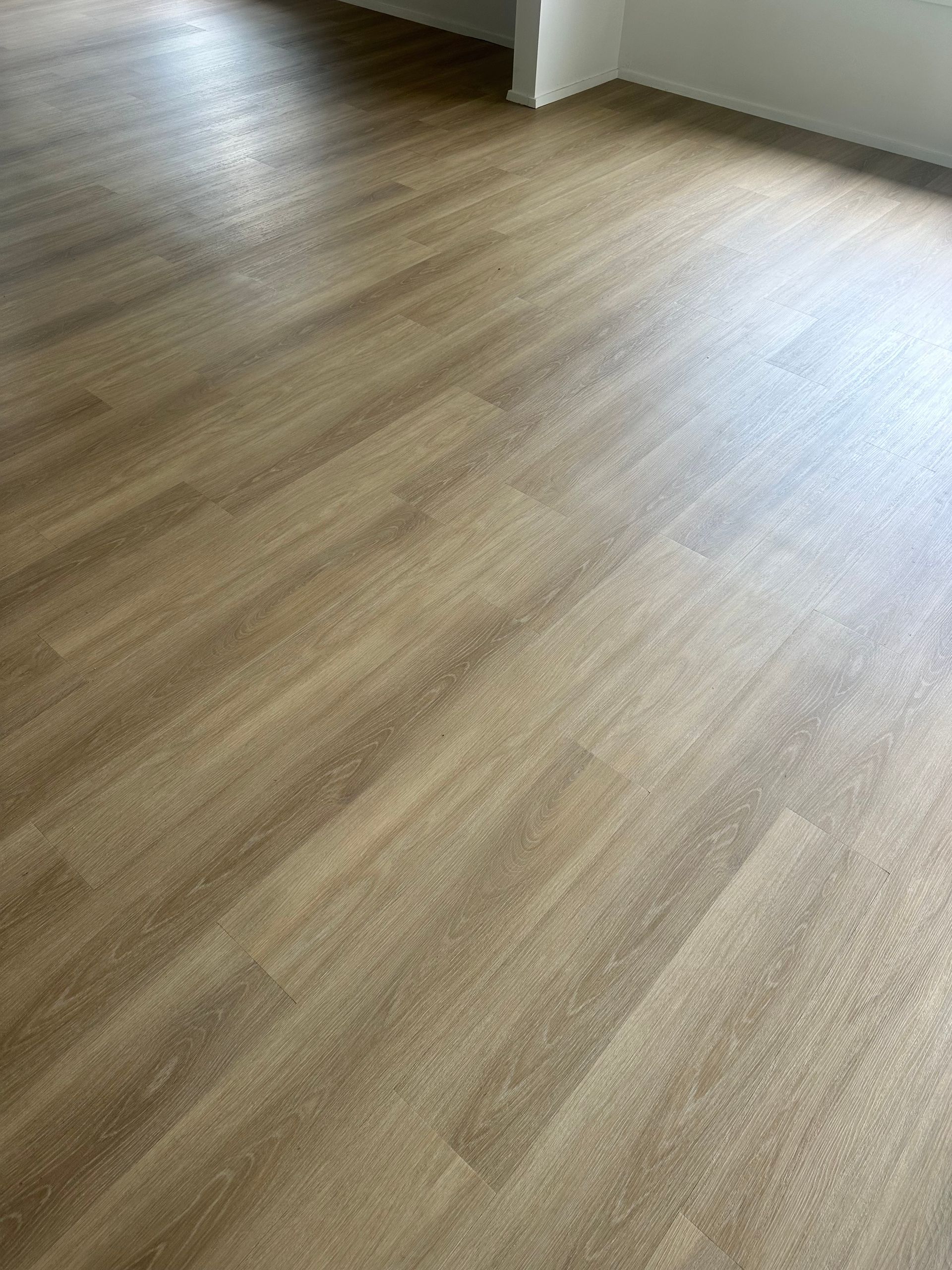 A Long Hallway With Wooden Floors And White Walls Leading To A Living Room — Charmhaven Carpets In Charmhaven, NSW