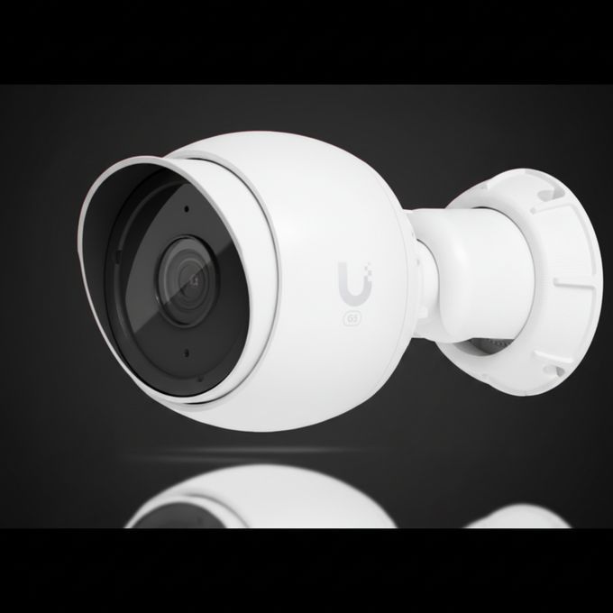 White outdoor security camera mounted on a wall, angled left on a dark background