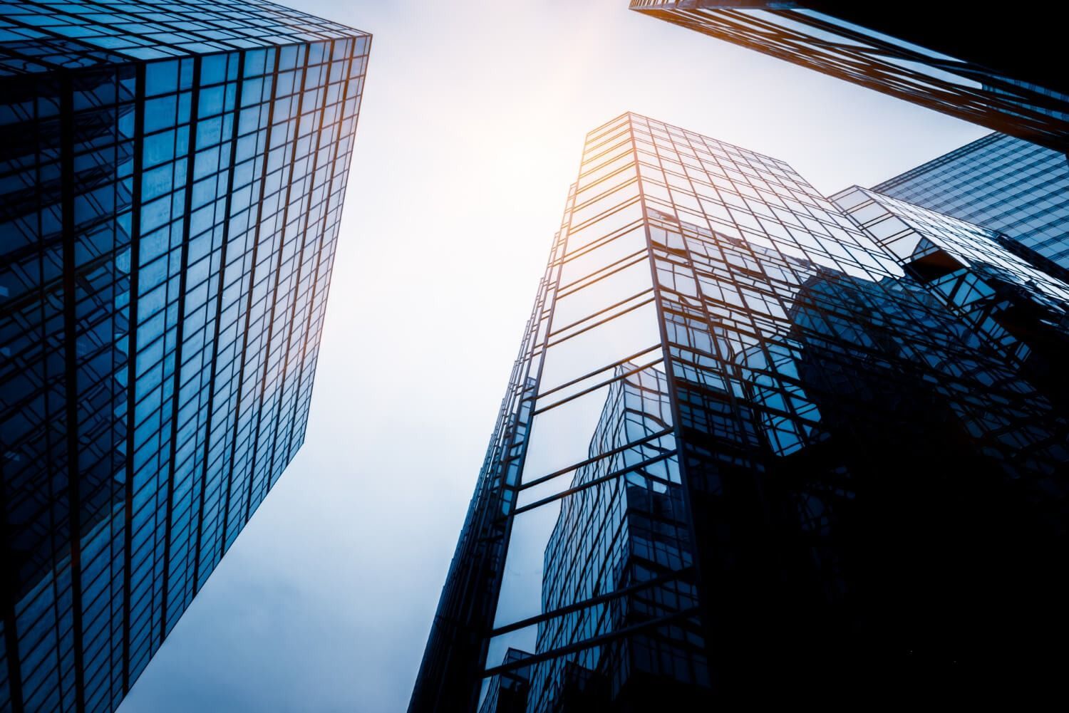 Skyscrapers with glass facades viewed from below against a bright sky