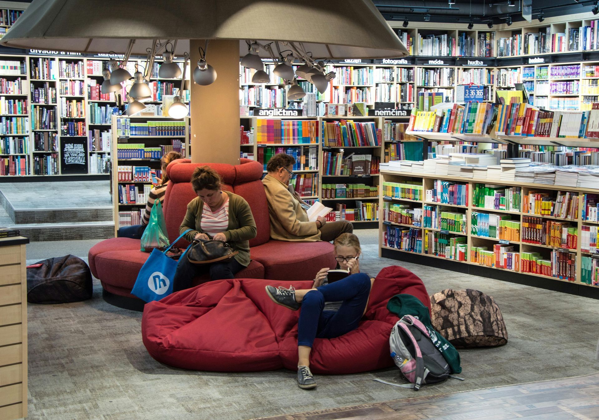 People sitting on red beanbags and chairs in a cozy library surrounded by bookshelves