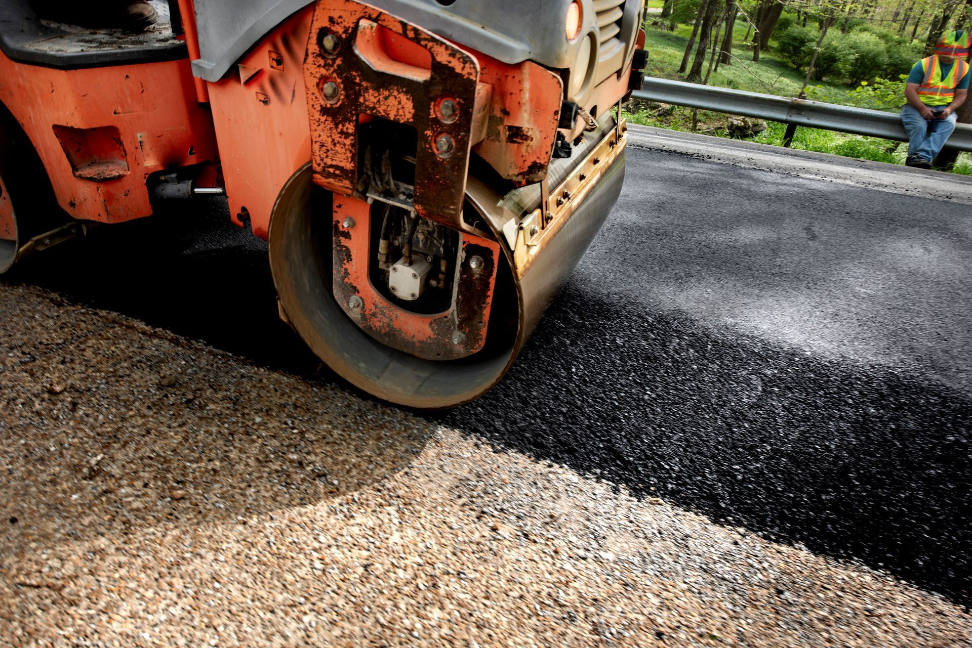 Road roller paving fresh asphalt on a rural road.