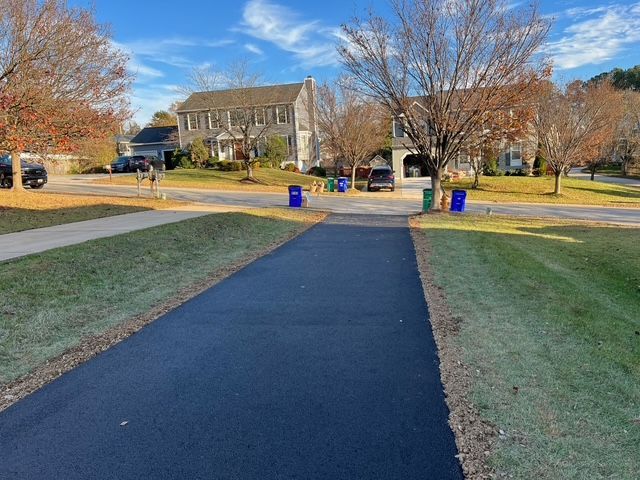 A newly paved driveway in a residential neighborhood with a house in the background.