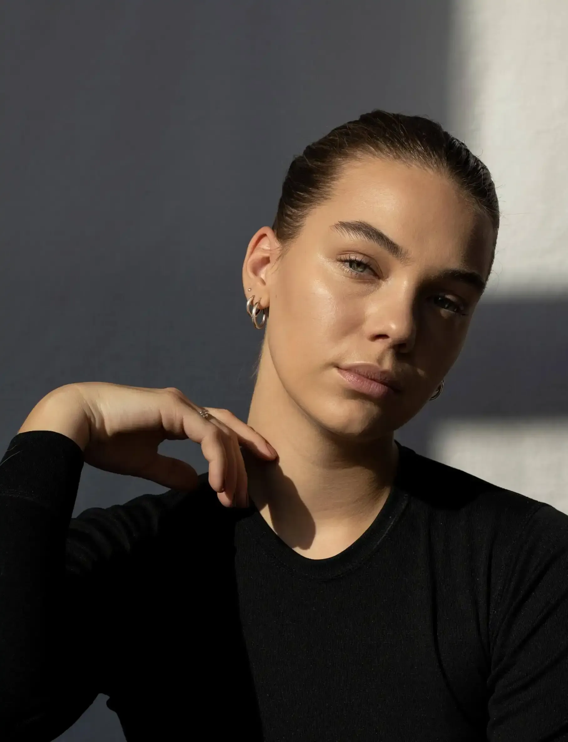 a woman in a black shirt has her hand on her neck