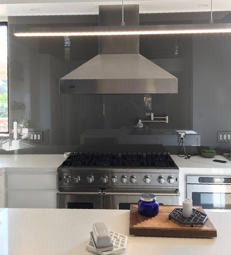 Modern kitchen with stainless steel range, hood, and island tray with blue jar and bowls
