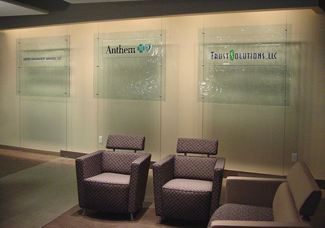 Office waiting area with two armchairs and glass wall signs, including Anthem and Tandem Services LLC.