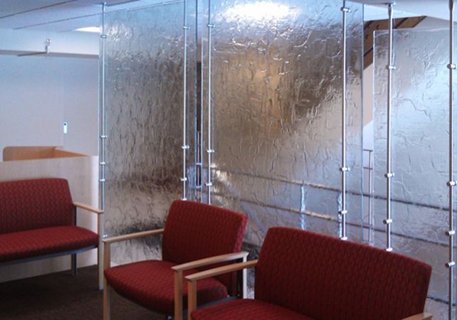 Modern waiting area with red chairs and frosted glass partitions in an office setting