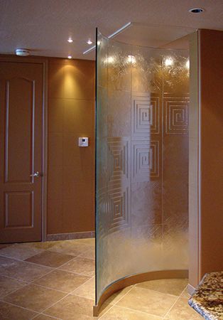 A bathroom with a curved glass shower door and a tiled floor.
