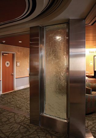 Hotel lobby with a frosted glass panel, wood-paneled walls, and carpeted seating area