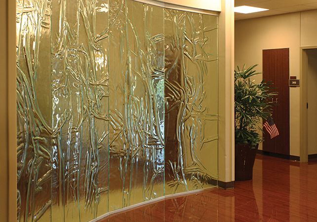 A hallway with a glass wall and a potted plant.