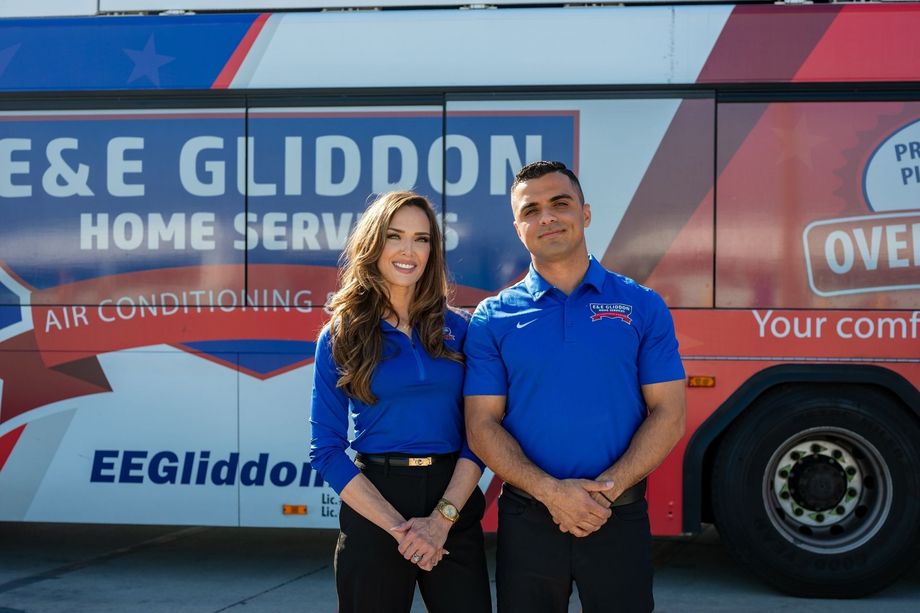 Two people standing in front of an E&E Gliddon home services van, smiling.