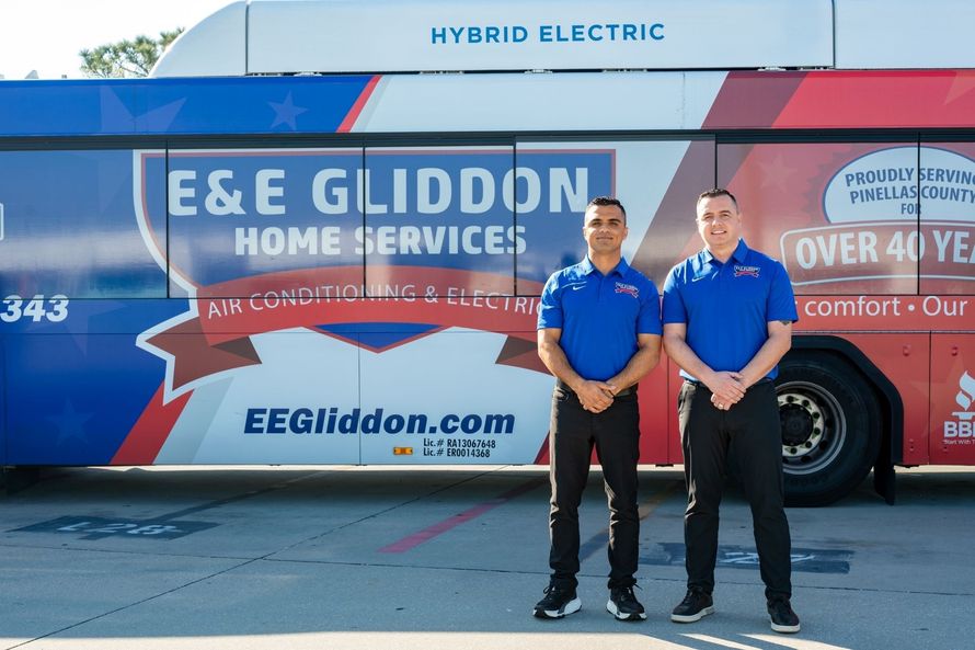 Two E&E Gliddon Home Services workers standing in front of a branded service bus