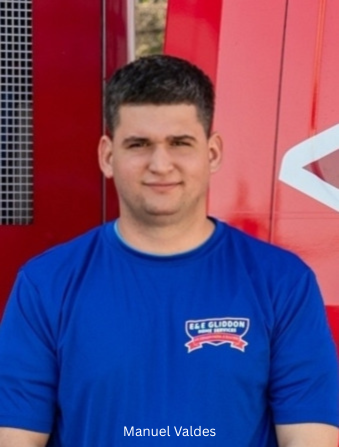 Man in blue shirt standing in front of a red wall, facing the camera.