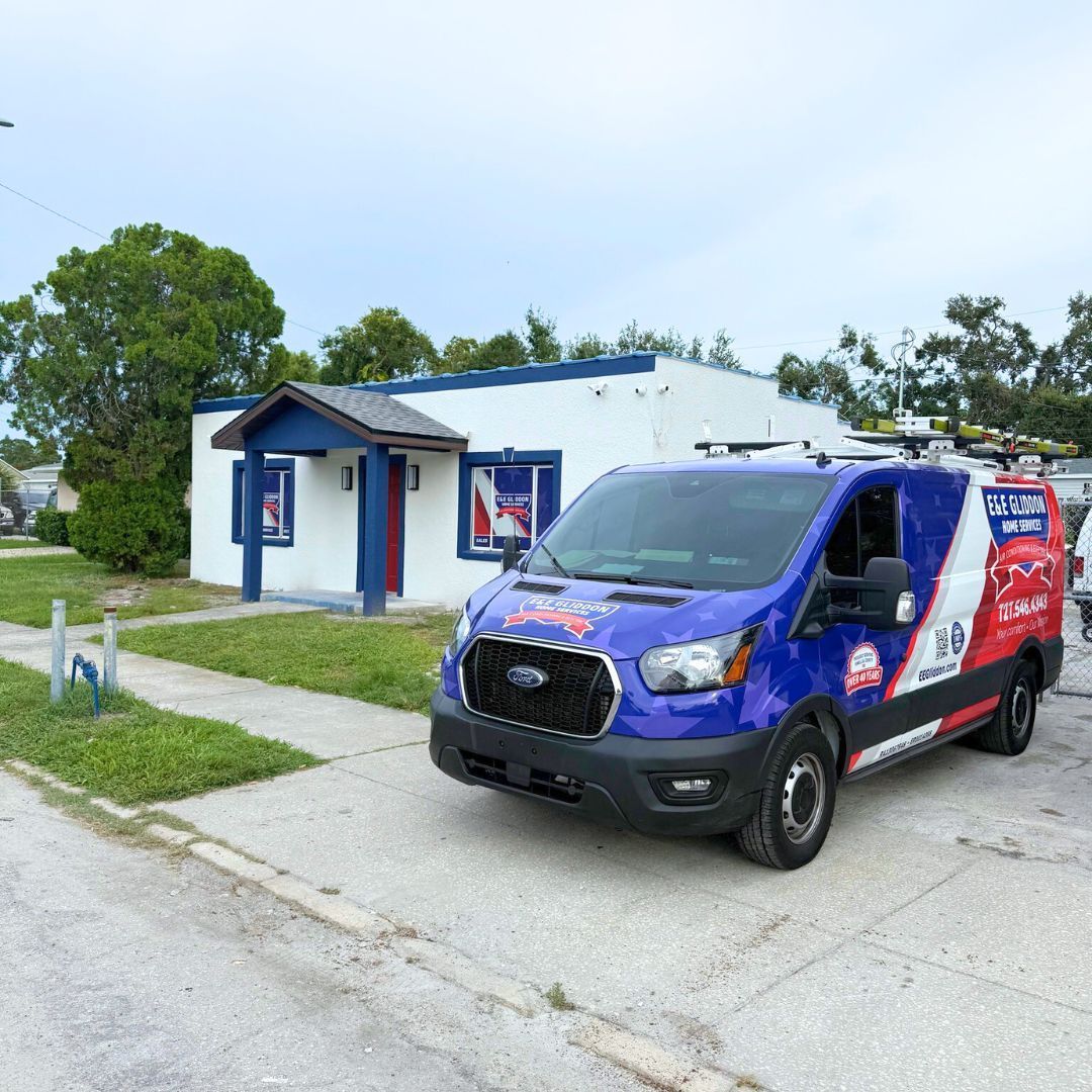 Blue and red service van parked outside a small white building on a quiet street