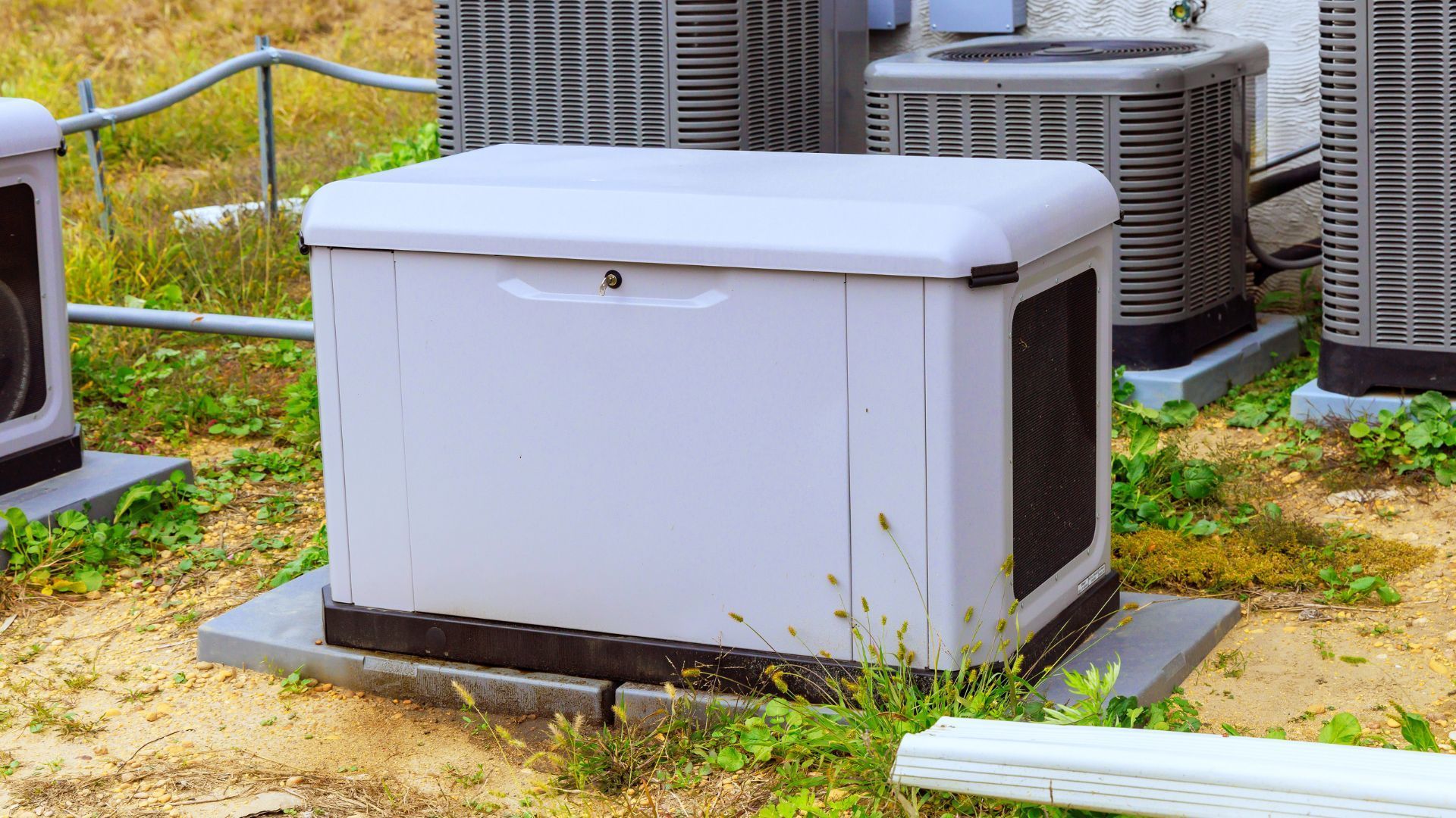 White outdoor utility box on a concrete pad near air-conditioning units in a grassy area.