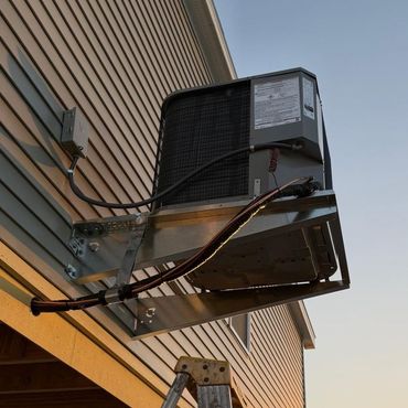 Wall-mounted HVAC condenser unit on a building exterior at dusk