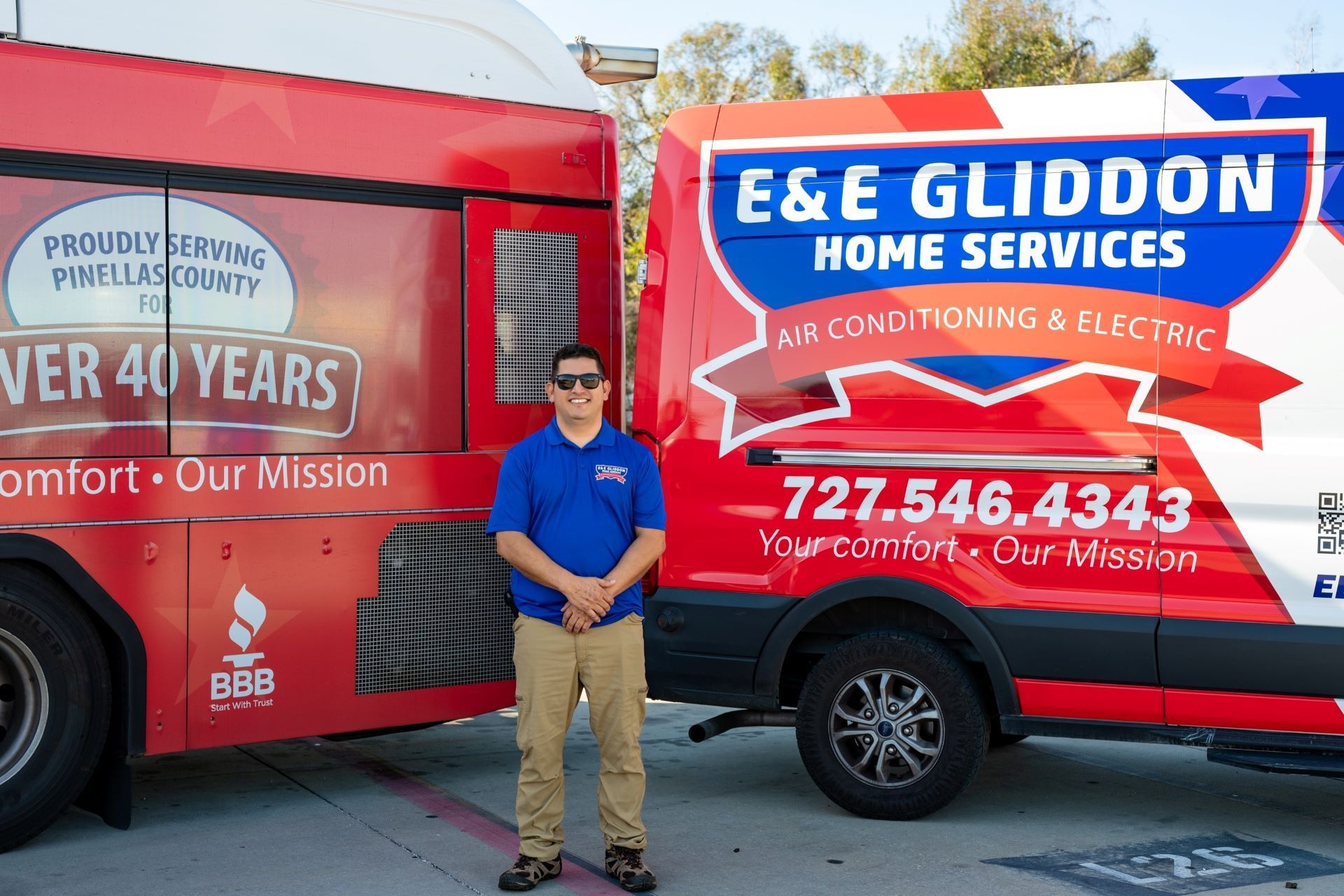 Technician standing between two red E&E Gliddon Home Services vans with company logos and phone number on display