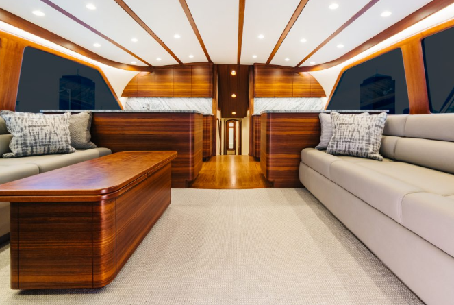 Interior of a boat cabin with wood paneling, light couches, and a coffee table.