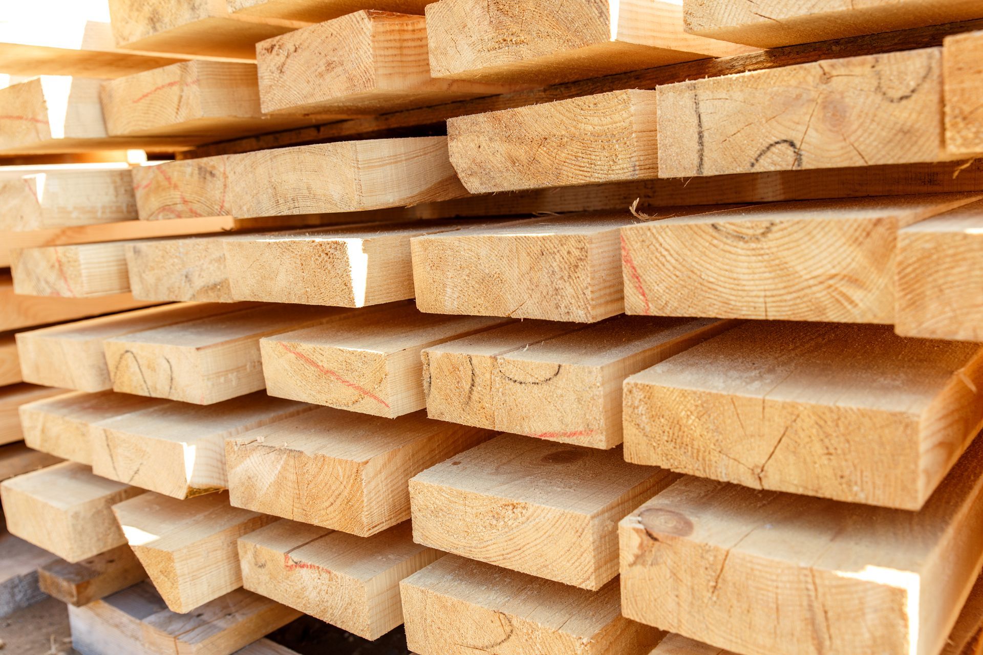 Stack of freshly cut wooden planks, light brown with visible grain.