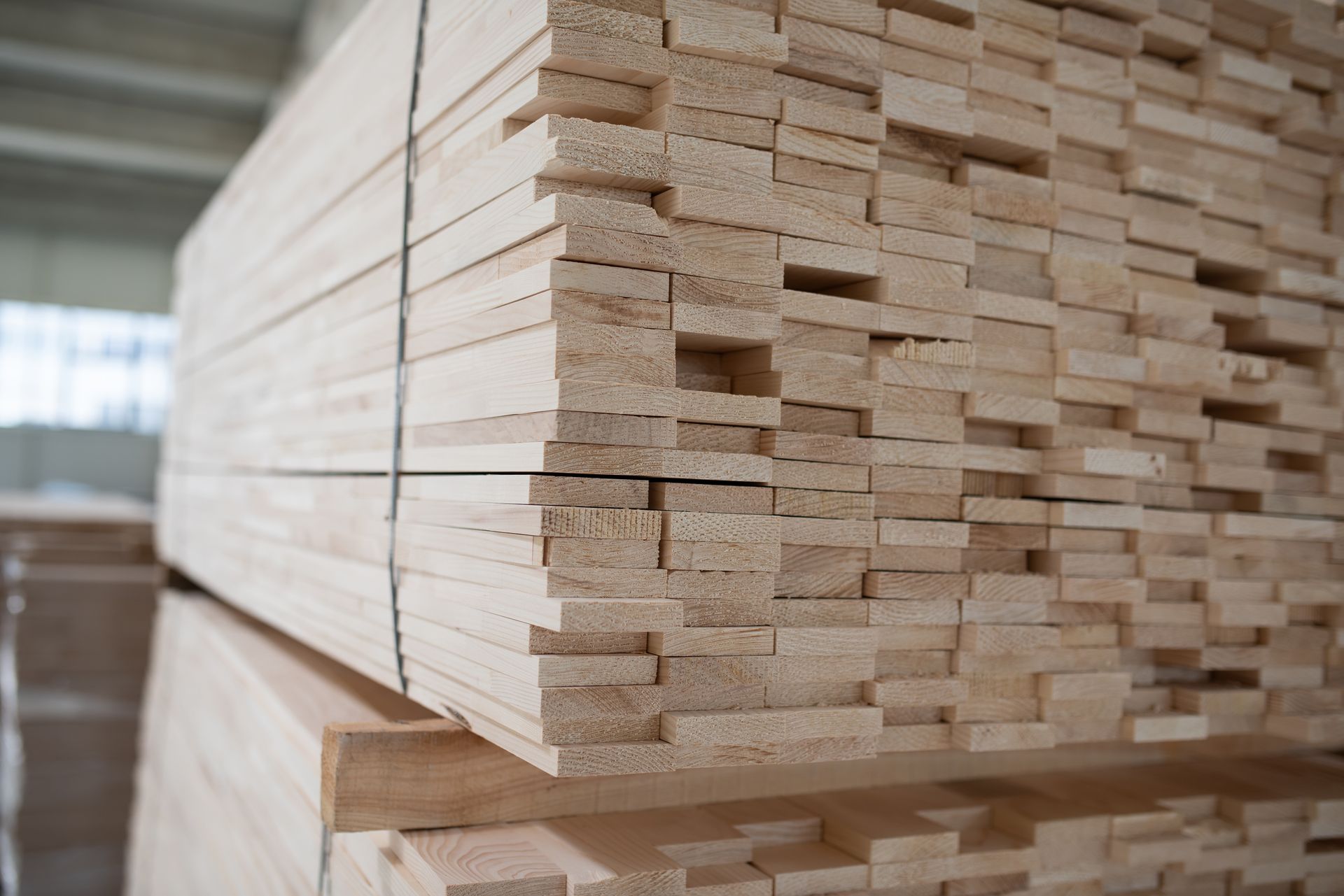 Stack of light-colored lumber in a warehouse.