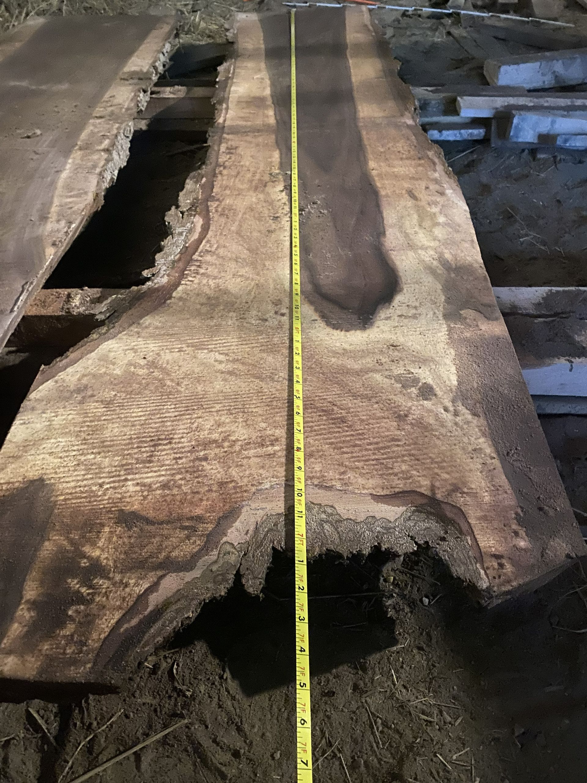 Two long wooden planks with live edges, a yellow tape measure runs the length.