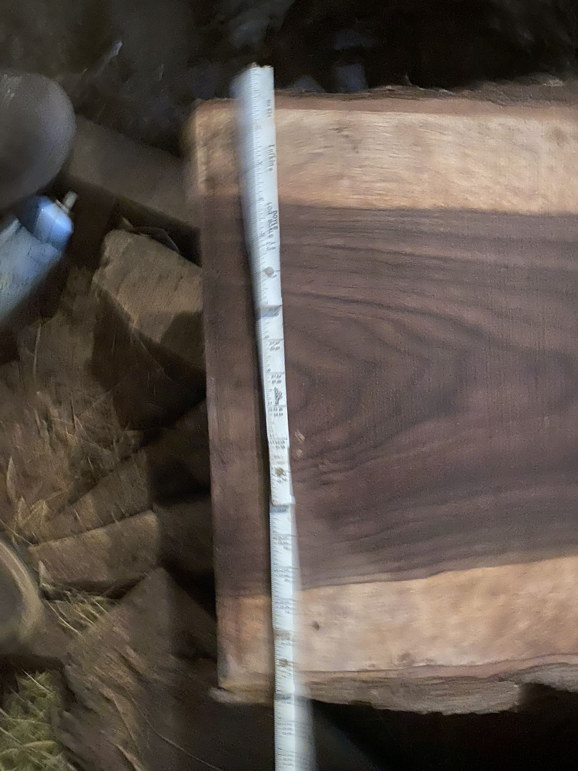 Tape measure next to a dark, wooden board showing grain.