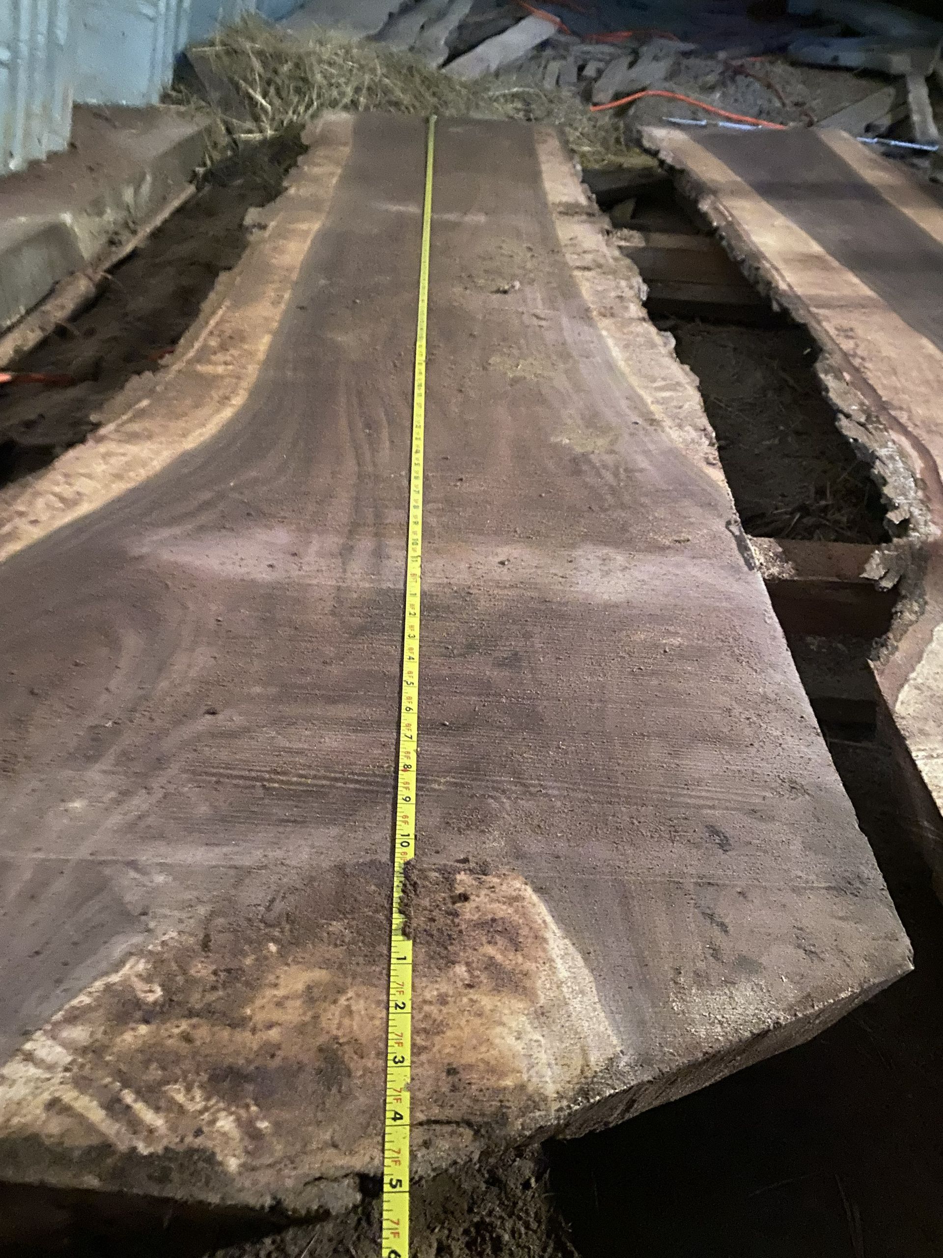 Large slab of dark wood with a yellow measuring tape running down the center.