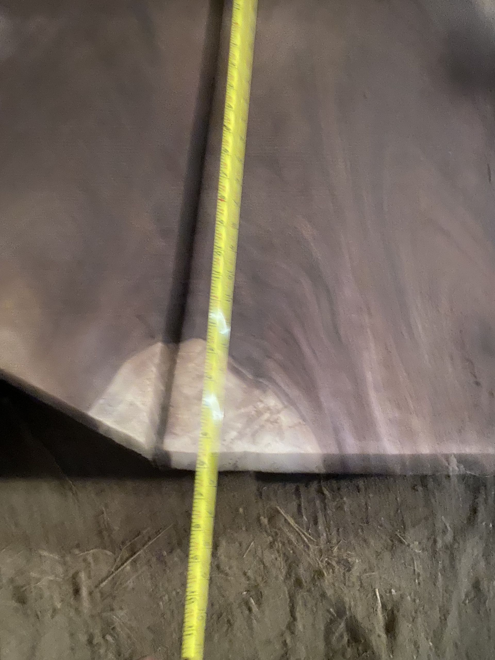 Yellow tape measure measuring a dark-colored wooden surface.