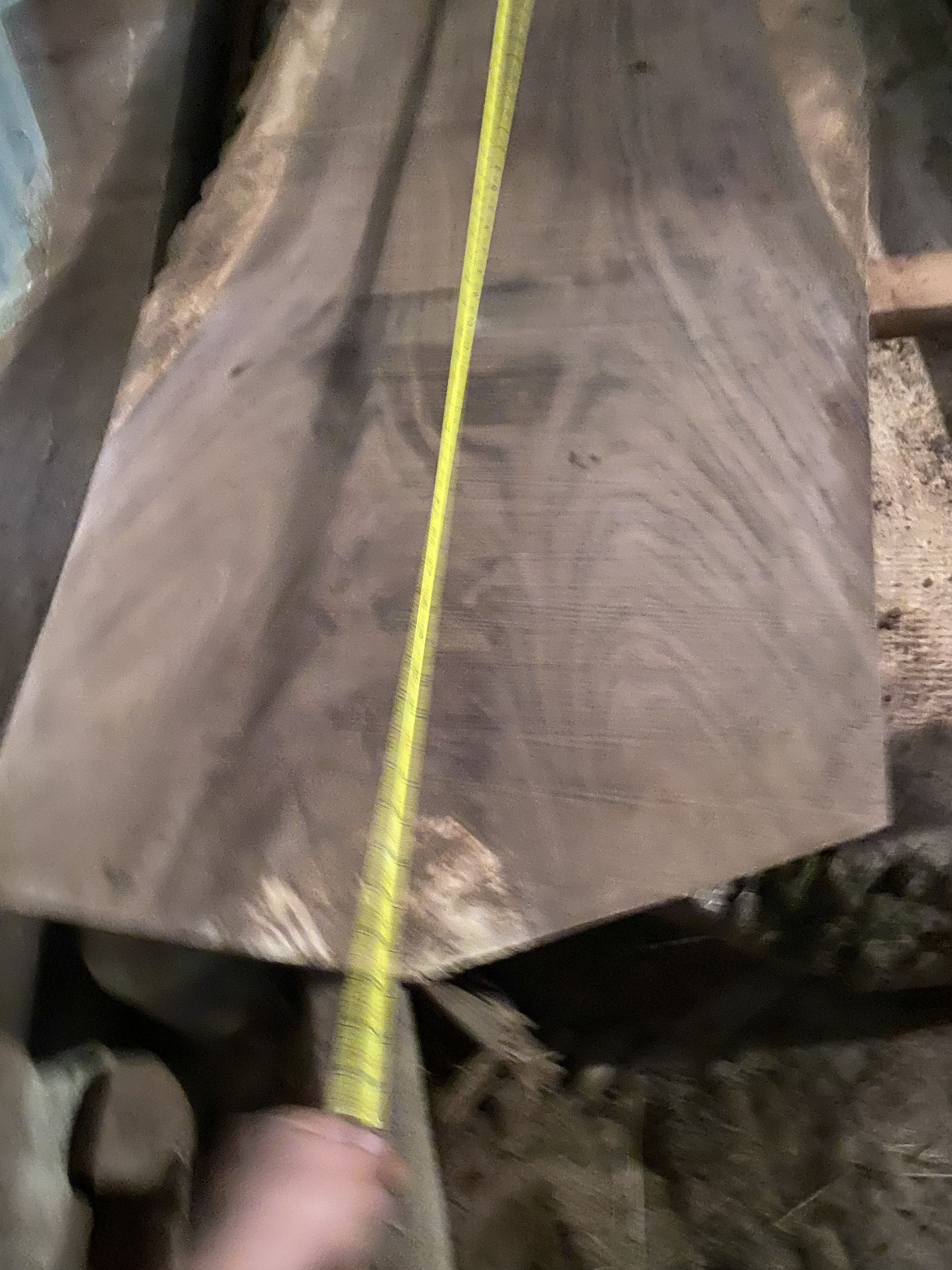 Wooden slab, measuring tape held by hand, measuring length.