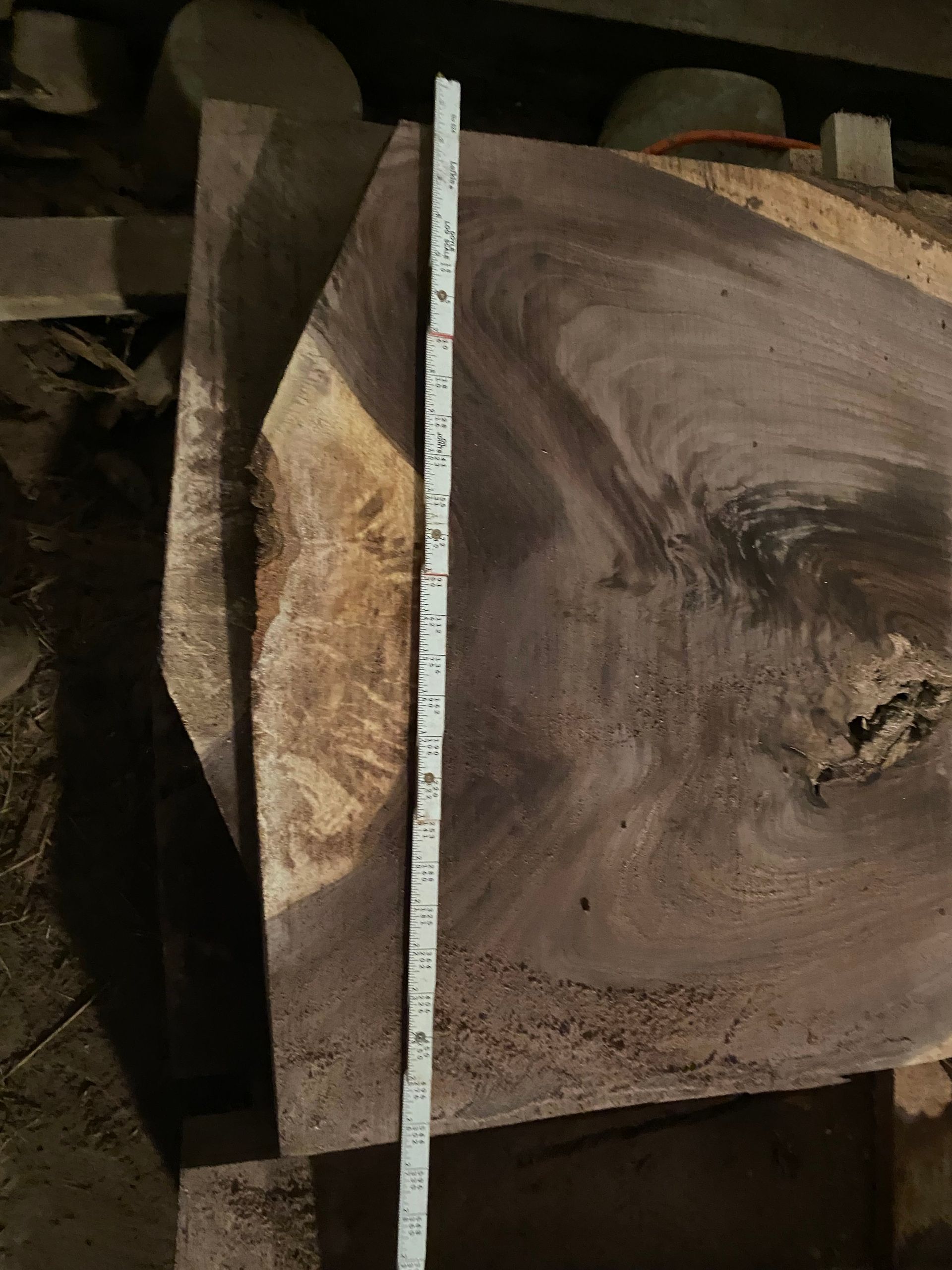 A dark wood slab with a measuring tape laid across it.