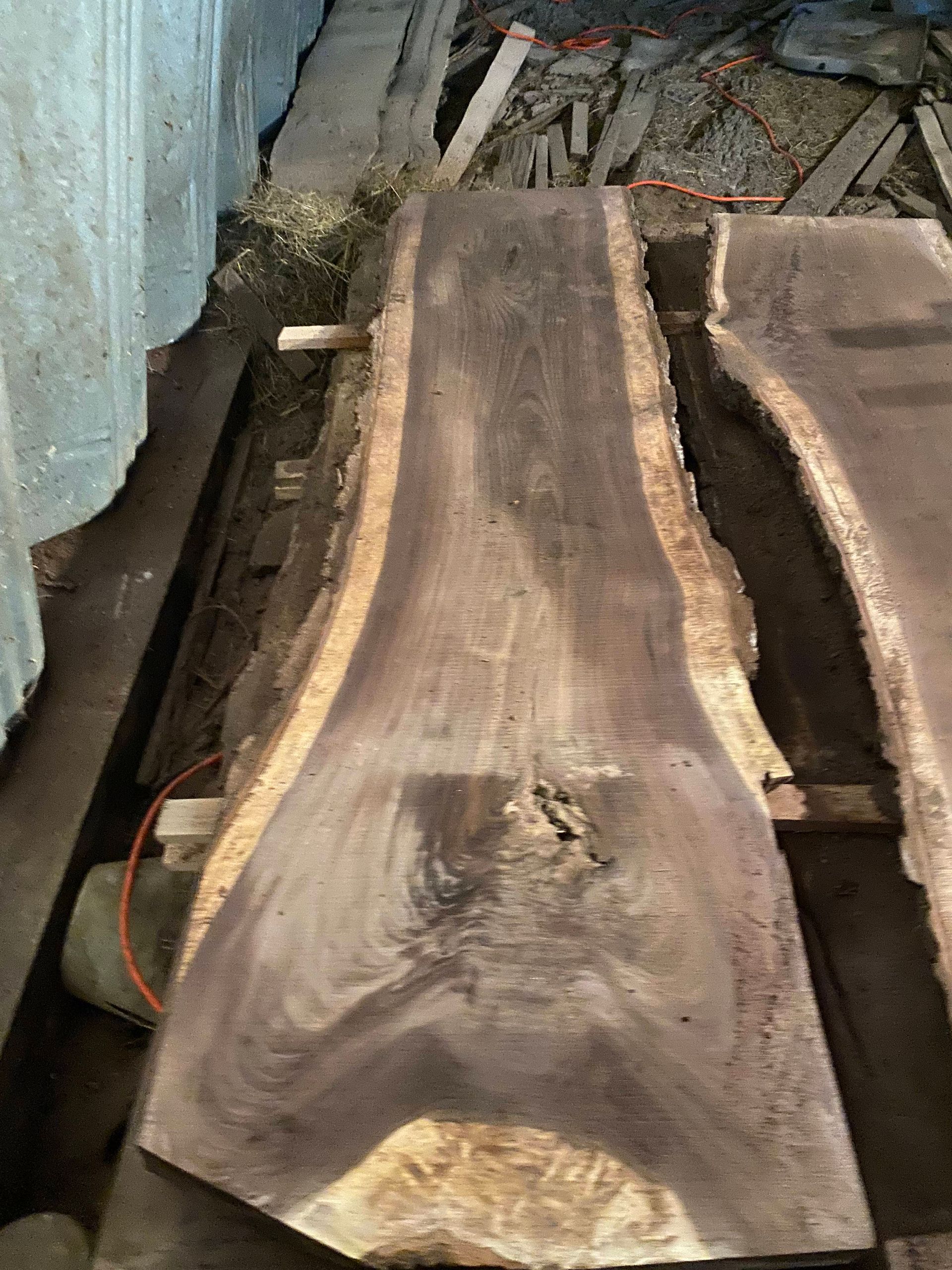 Dark brown wood slab with live edge, lying flat.