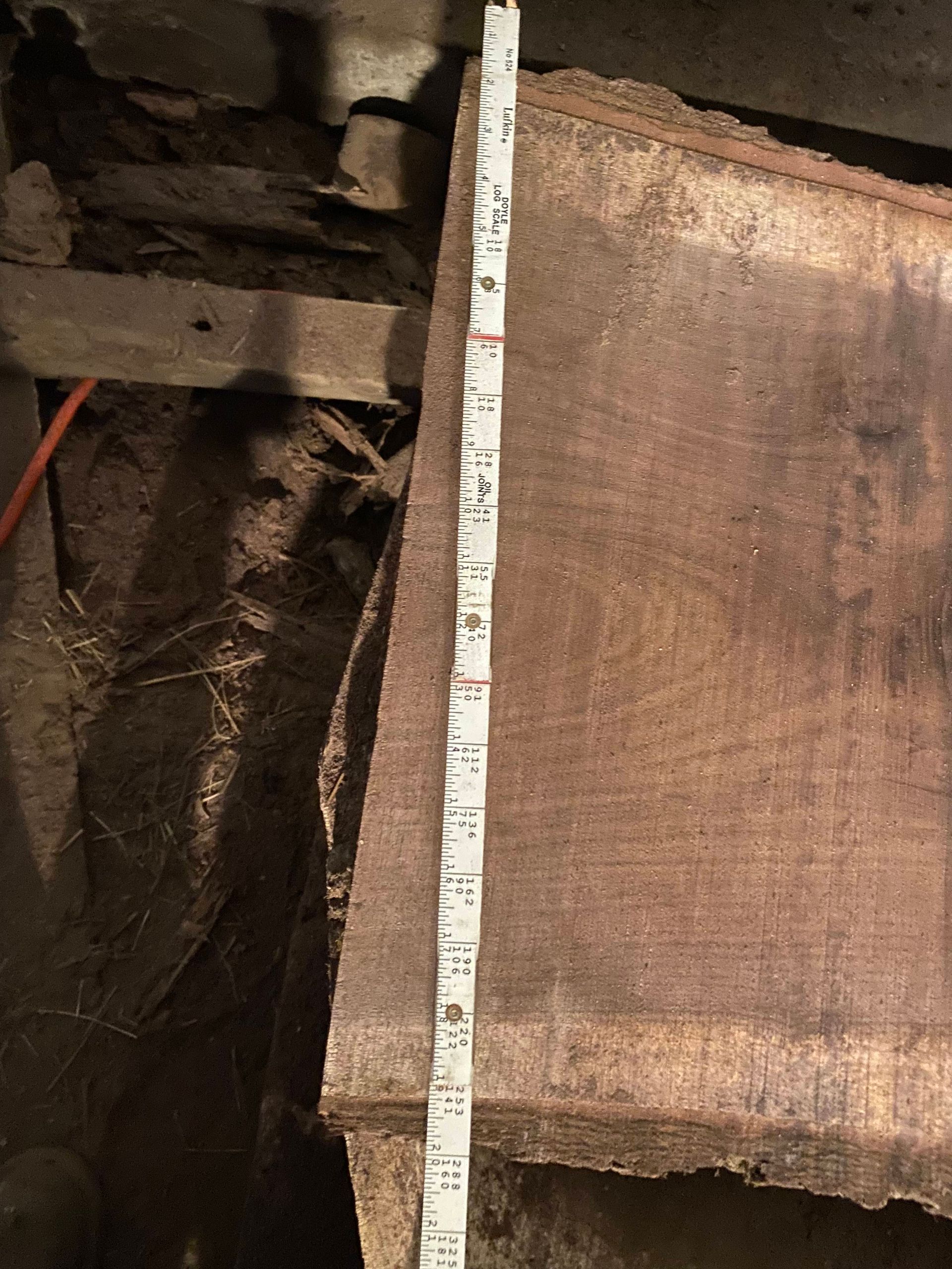 A dark, wooden plank with a ruler beside it, measuring approximately 30 inches.